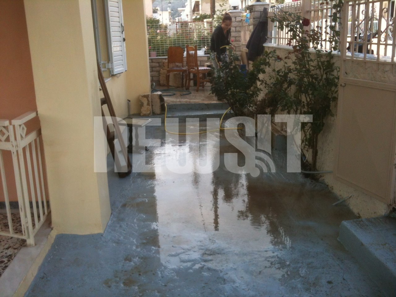 Μια γυναίκα προσπαθεί να καθαρίσει την αυλή της - ΦΩΤΟ NEWSIT
