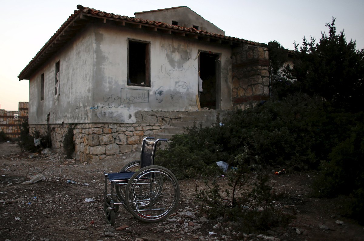 Ένα αναπηρικό αμαξίδιο μπροστά από ένα ερειπωμένο σπίτι που μένουν έστω για λίγο πολλές οικογένειες