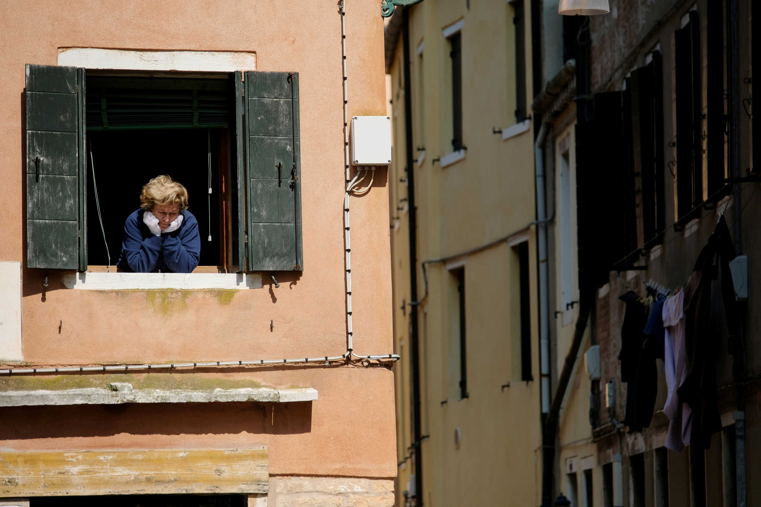 FILE PHOTO: A woman looks out of an apartment window as Italians remain under lockdown to prevent the spread of the coronavirus disease (COVID-19) in Venice, Italy April 4, 2020. REUTERS