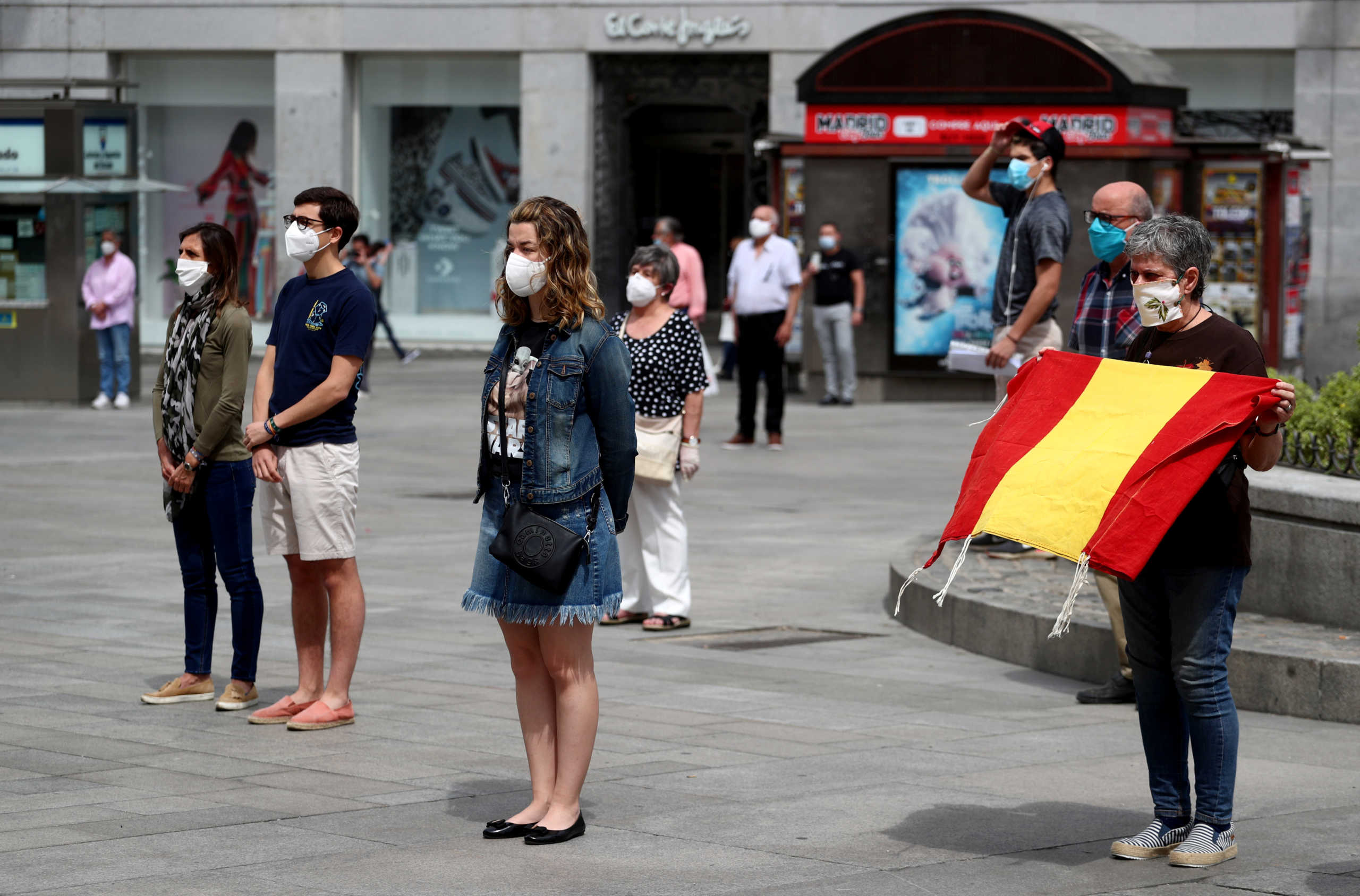 People wearing protective face masks stand during a daily minute of silence to commemorate victims of the coronavirus disease (COVID-19), at Puerta del Sol square in Madrid, Spain, May 26, 2020. REUTERS