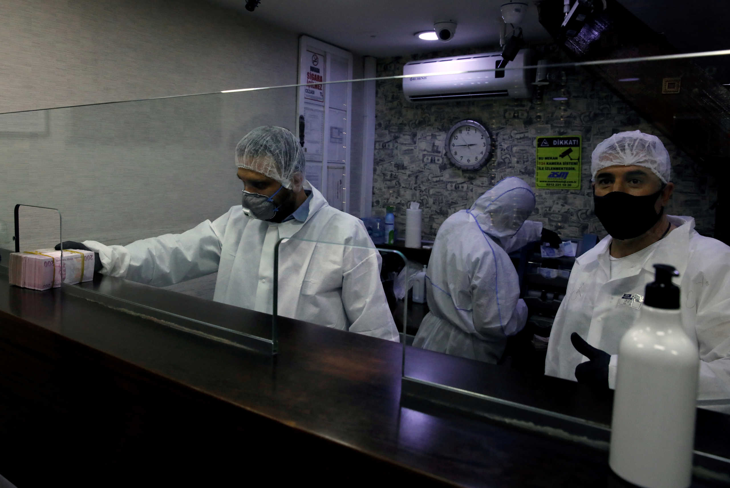 FILE PHOTO: Cashiers in protective suits work in an exchange office at Grand Bazaar, which has been closed since March 23 and will re-open completely on June 1, amid the spread of the coronavirus disease (COVID-19), in Istanbul, Turkey, May 8, 2020. REUTERS