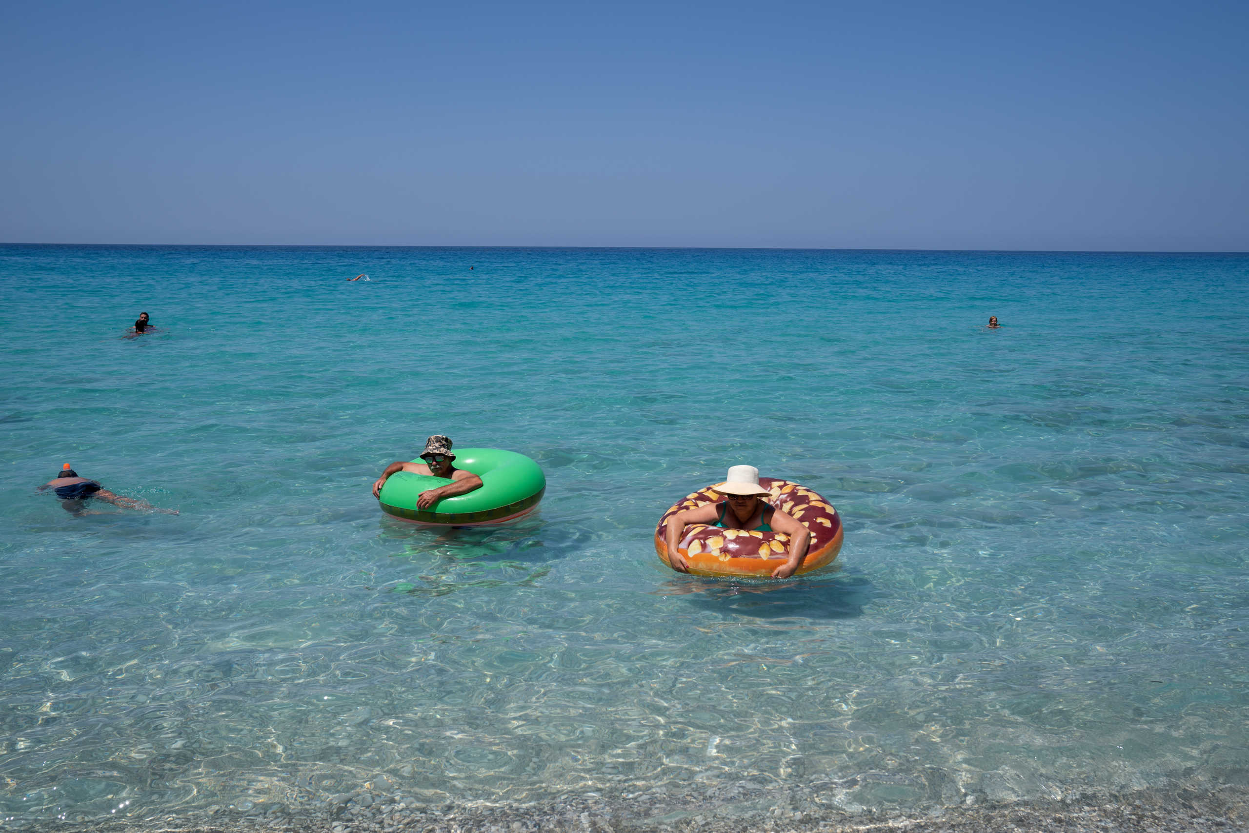 People swim at Agios Nikitas beach, following the easing of measures against the spread of the coronavirus disease (COVID-19), on the island of Lefkada, Greece, July 25, 2020. Picture taken July 25, 2020. REUTERS