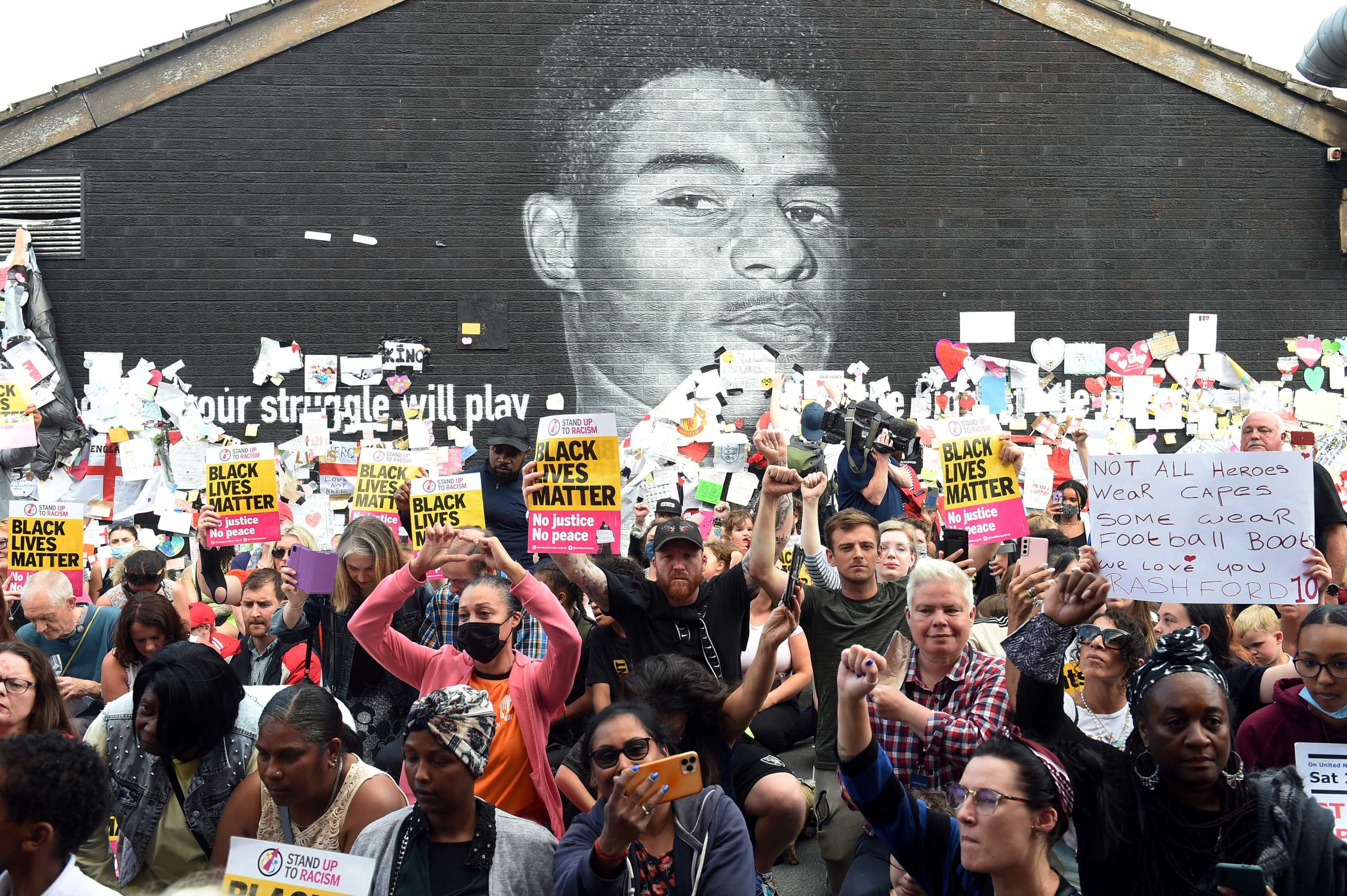 Soccer Football - Stand Up to Racism Demonstration at the Marcus Rashford mural after it was defaced following the Euro 2020 Final between Italy and England - Withington, Manchester, Britain - July 13, 2021 Demonstrators hold up "Stand Up To Racism" banners in front of the Marcus Rashford mural after it was defaced following the Euro 2020 Final between Italy and England  REUTERS