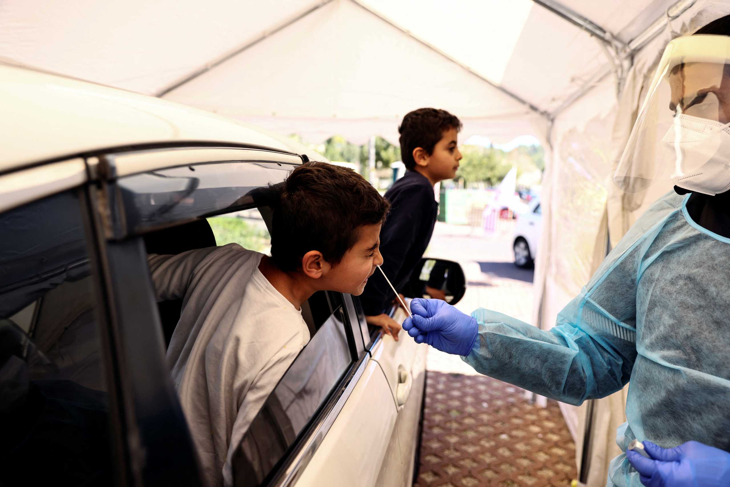 A boy is tested for the coronavirus disease (COVID-19) at a drive-through site as Israel faces a surge in Omicron variant infections, in Jerusalem, January 10, 2022. REUTERS