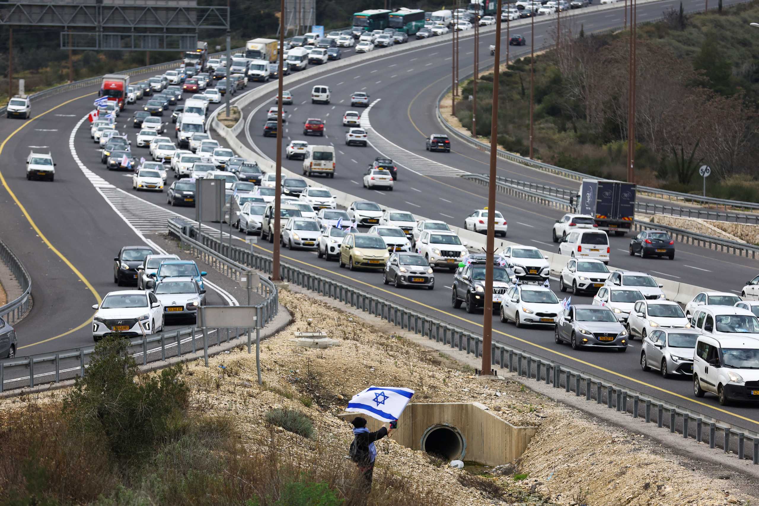 A demonstrator waves an Israeli flag as an Israeli "Freedom Convoy" heads towards Jerusalem to protest against restrictions to contain the spread of the coronavirus disease (COVID-19), near Ein Hemed, February 14, 2022. REUTERS