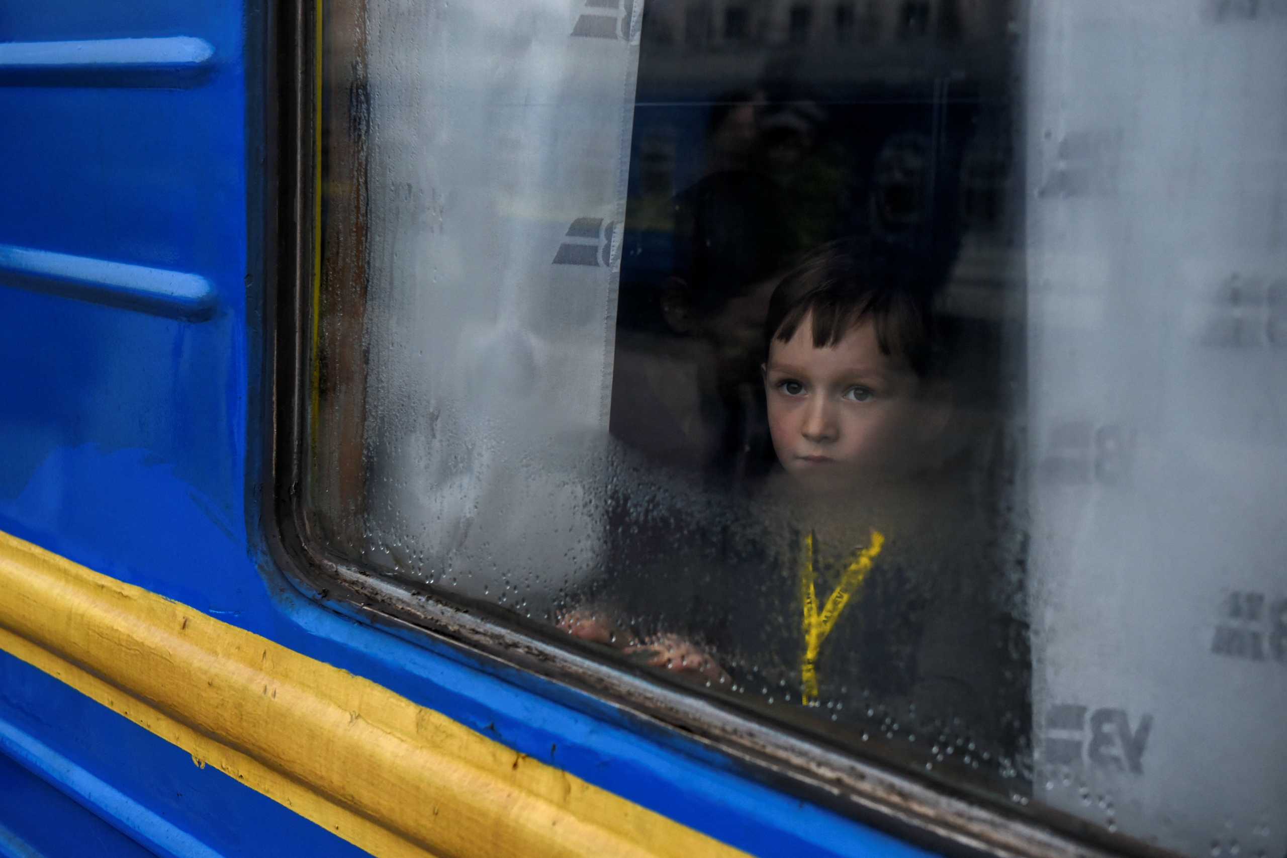 A boy looks through a train window as passengers, including people fleeing Russia's invasion of Ukraine, board a train to leave the city of Odessa, Ukraine, March 6, 2022. REUTERS