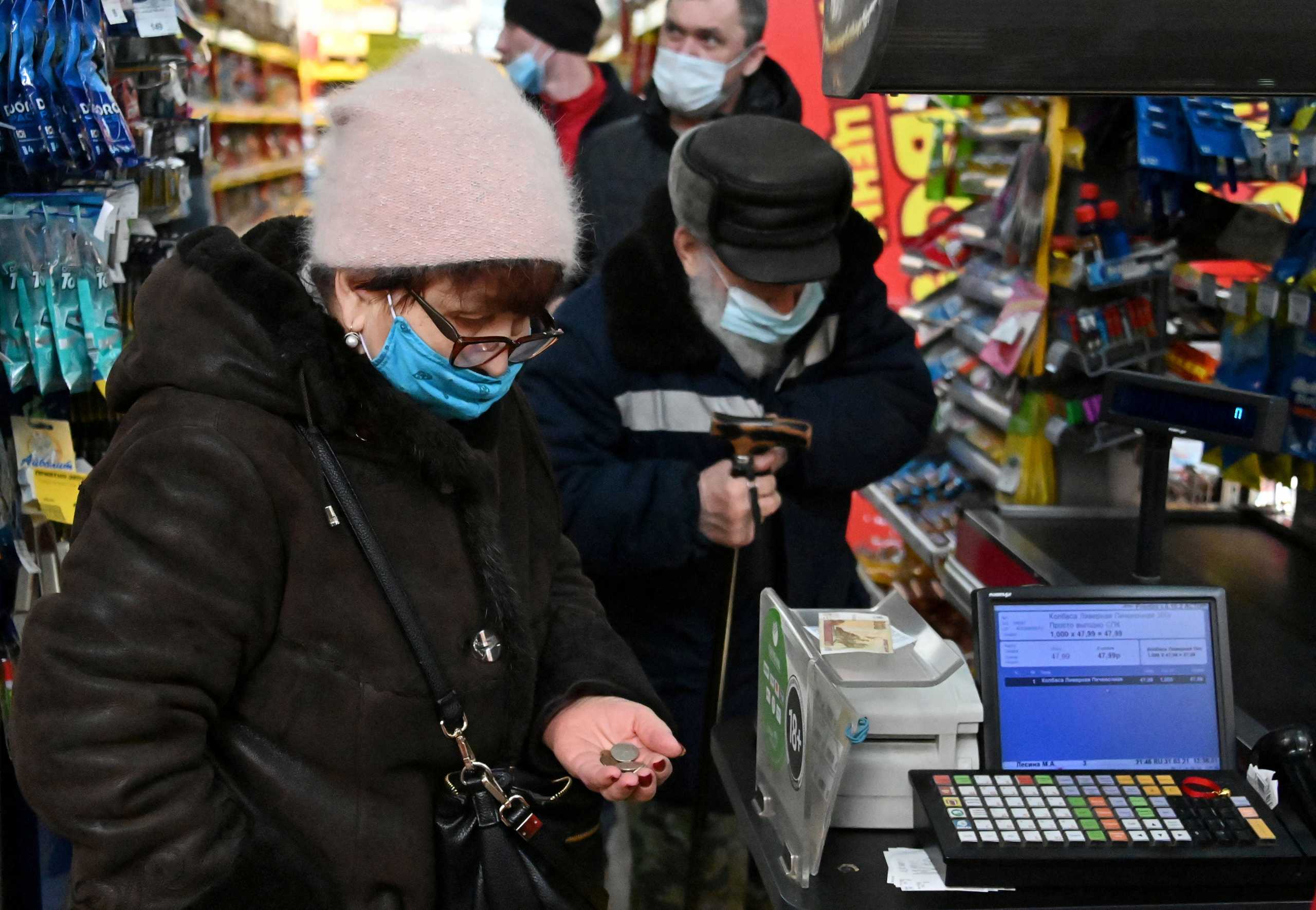 FILE PHOTO: A woman wearing a face mask pays at the checkout in a grocery store in Omsk, Russia March 31, 2021. REUTERS