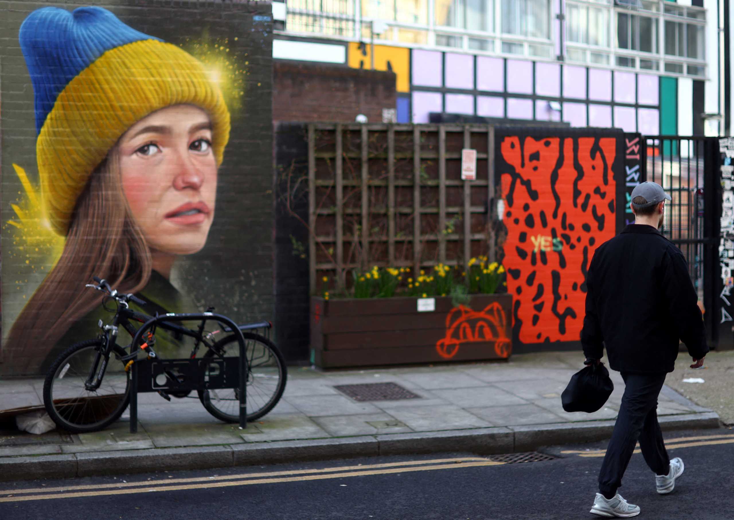 A man walks past a mural in support of Ukraine by artist WOSKerski, as Russia's invasion of Ukraine continues, in London, Britain, March 14, 2022. REUTERS