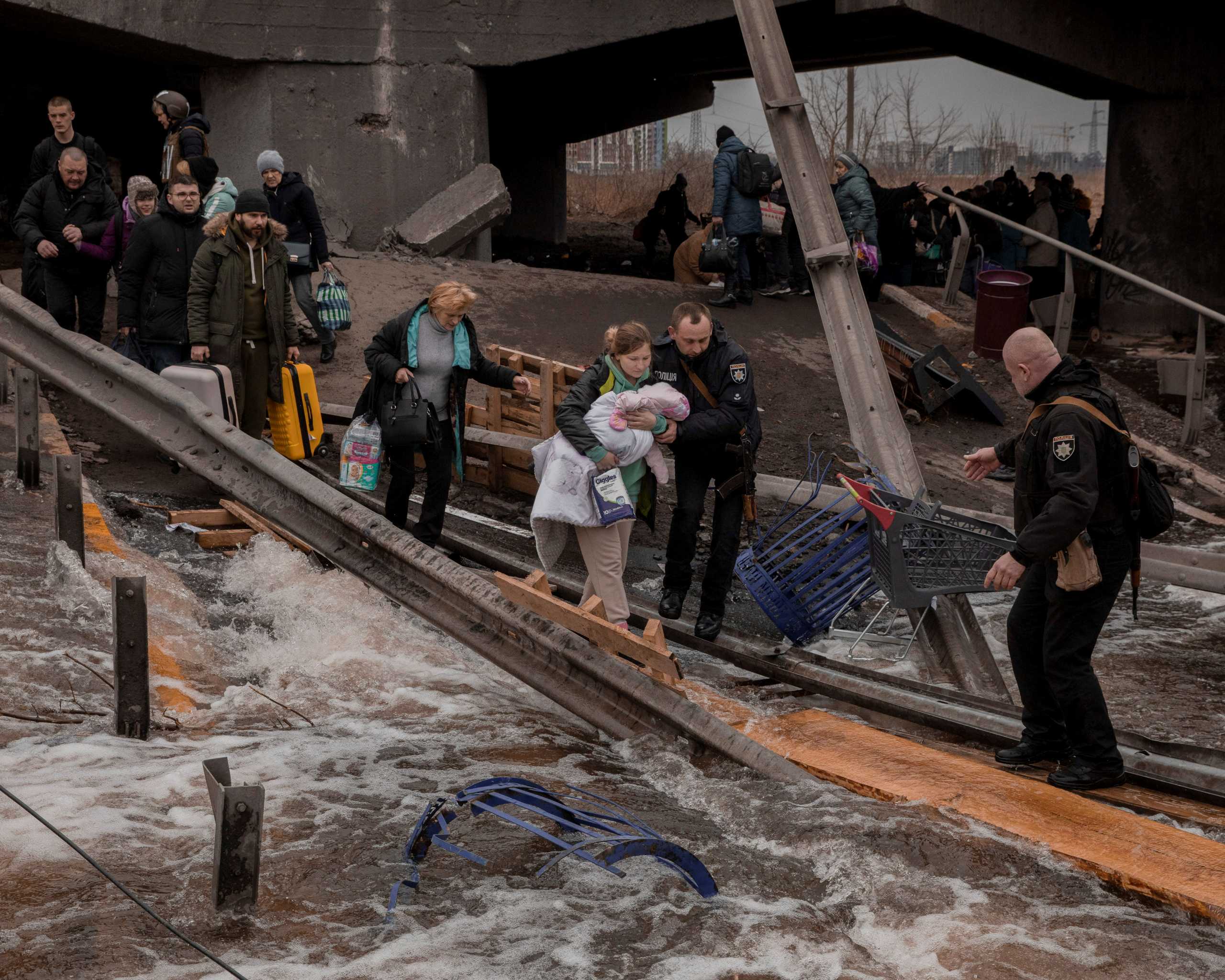 Local residents cross a destroyed bridge as they evacuate from their town in Irpin, near Kyiv, Ukraine March 7, 2022. Jedrzej Nowicki