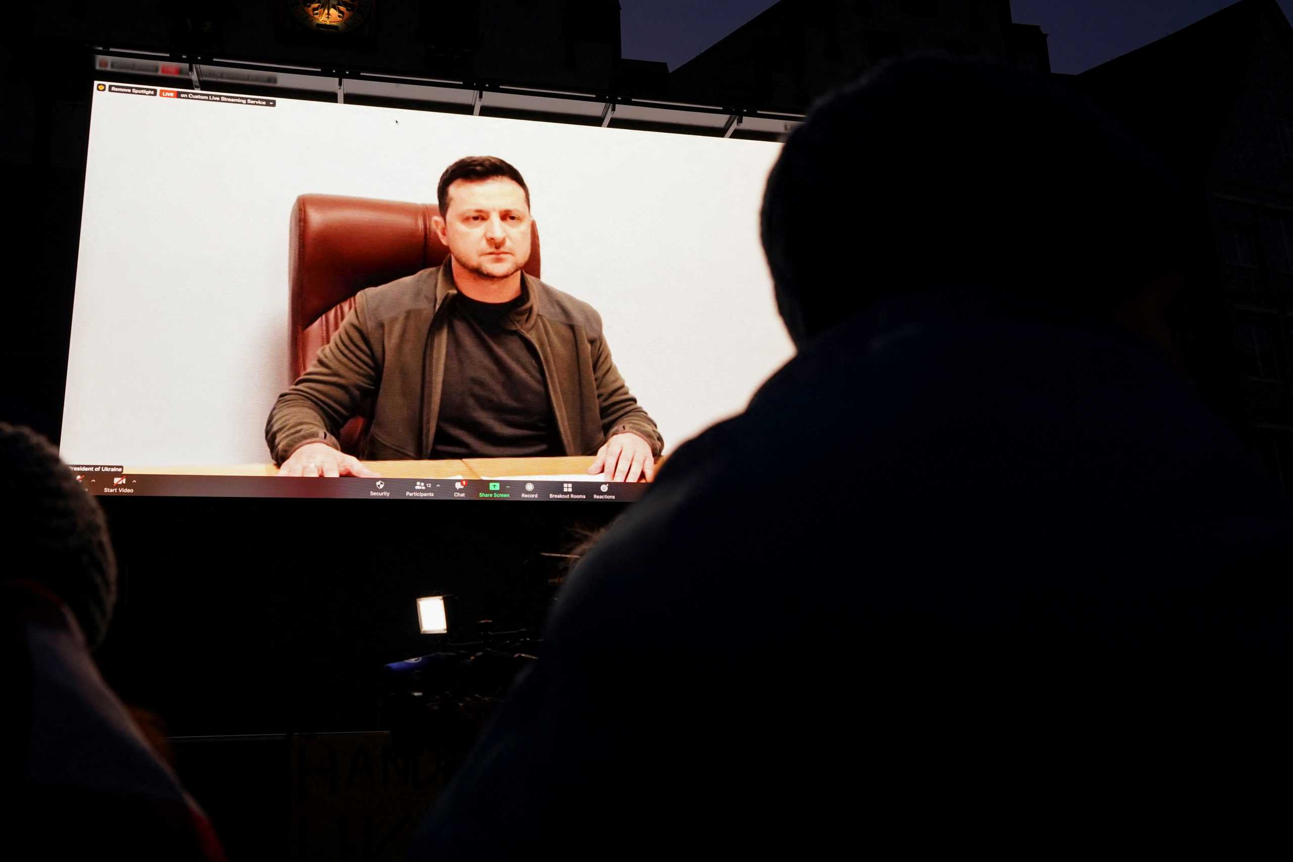 People watch Ukrainian President Volodymyr Zelenskiy on a screen addressing anti-war demonstrations in several European cities including Frankfurt, Vienna, Lyon, Tbilisi, Vilnius and Prague, as Russia's invasion of Ukraine continues, at the famous city centre Roemerberg, in Frankfurt, Germany, March 4, 2022.   REUTERS