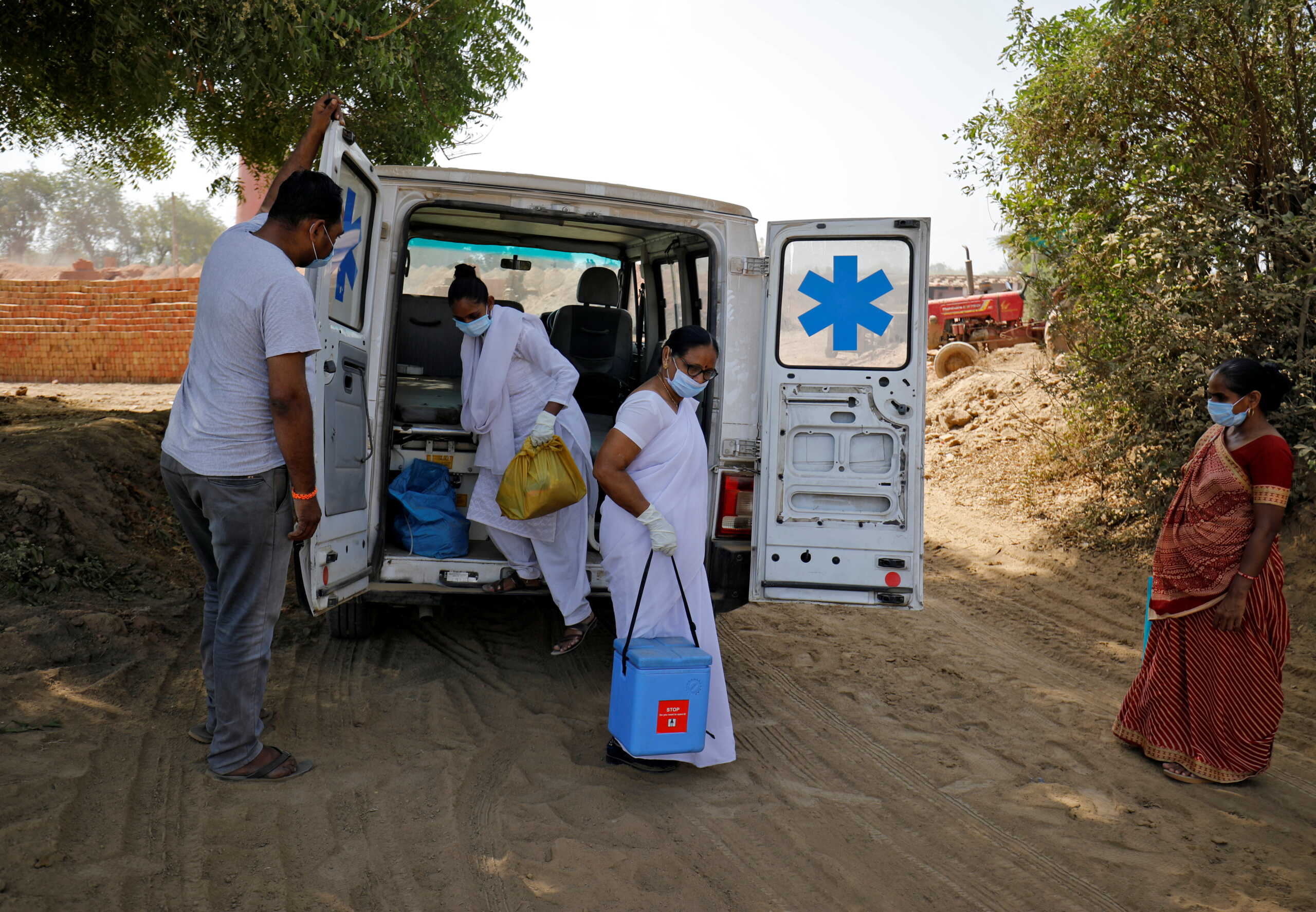 Healthcare workers arrive with doses of COVISHIELD, a coronavirus disease (COVID-19) vaccine manufactured by Serum Institute of India, to be administered to workers of a brick kiln at Kavitha village on the outskirts of Ahmedabad, India, April 8, 2021. REUTERS