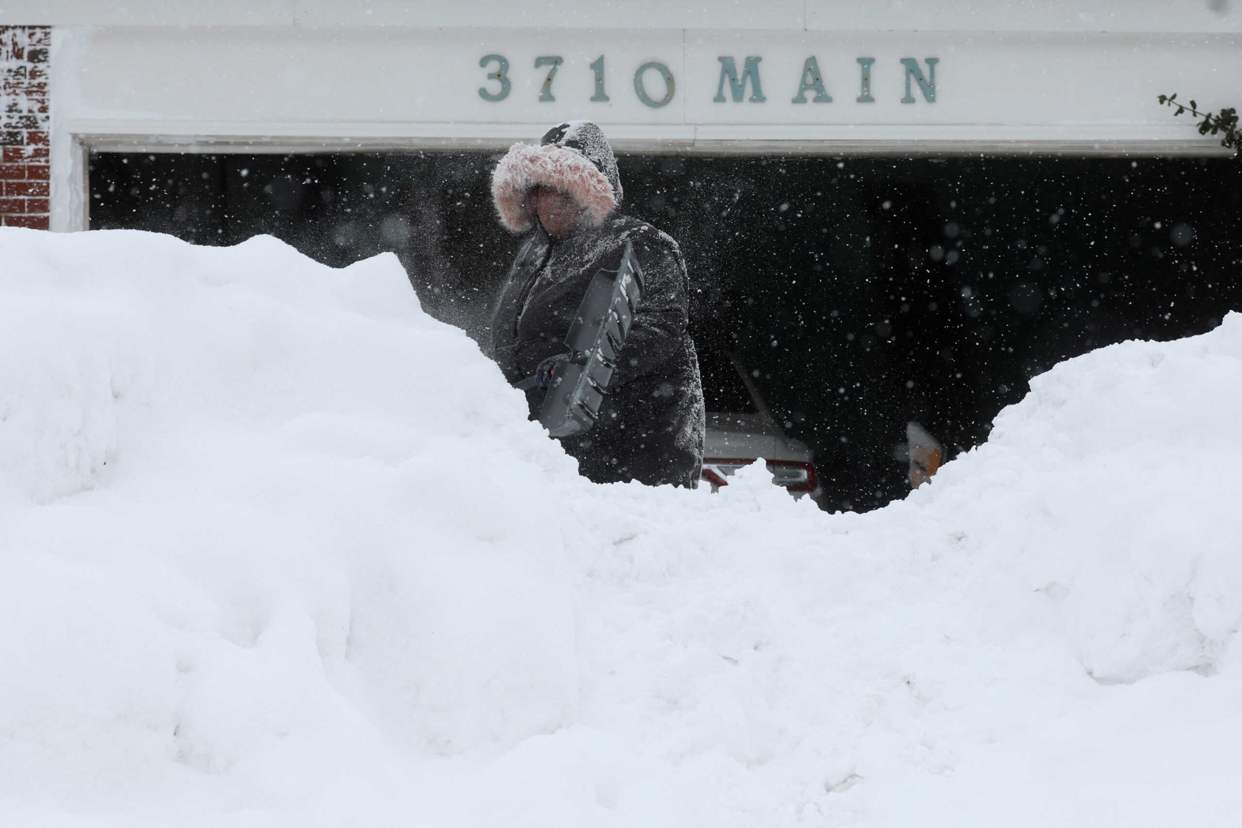 A woman clears snow from her driveway following a winter storm that hit the Buffalo region, in Amherst, New York, U.S., December 26, 2022.  REUTERS