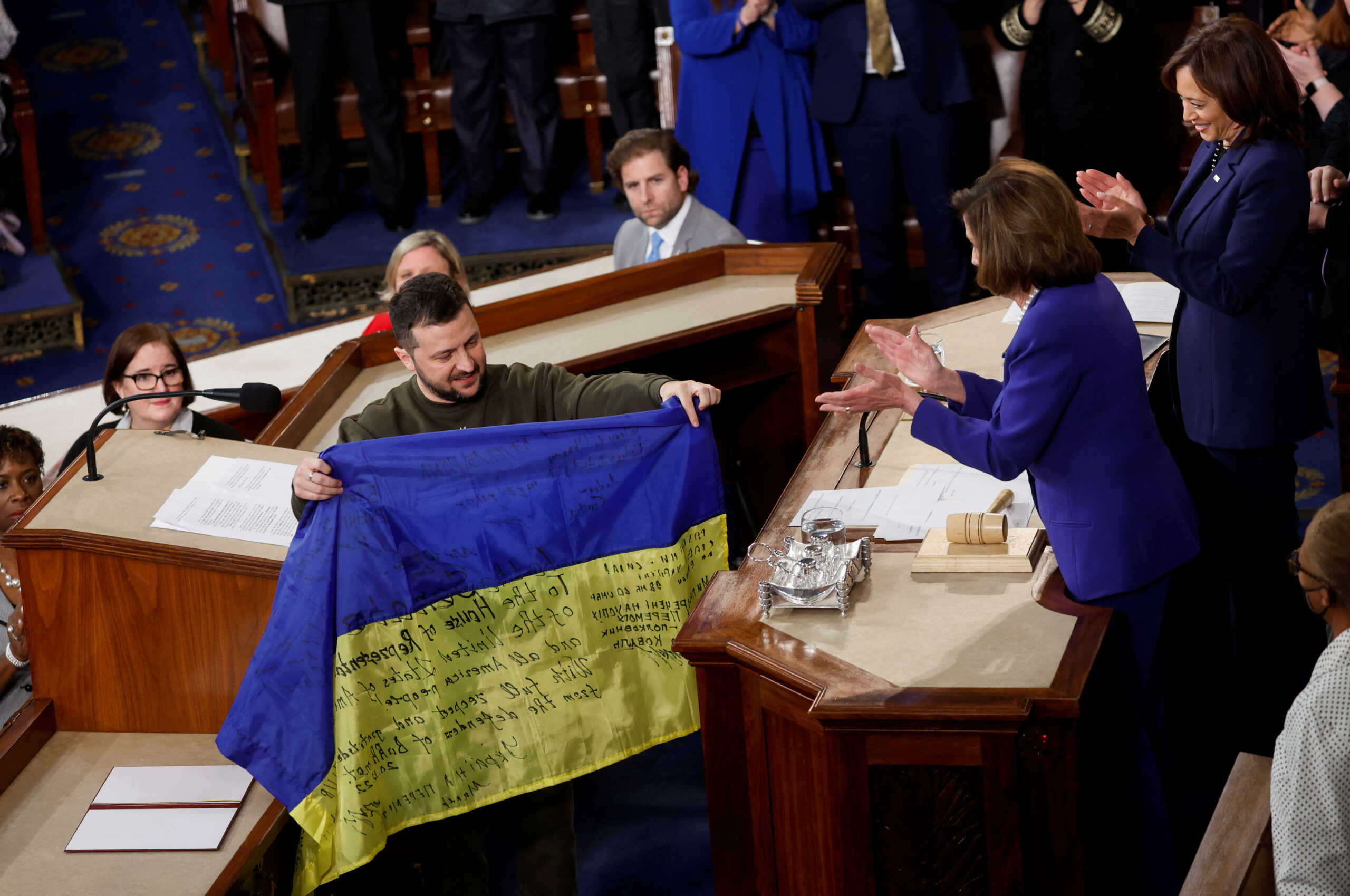 Ukraine's President Volodymyr Zelenskiy presents a Ukrainian flag given to him by defenders of Bakhmut to U.S. House Speaker Nancy Pelosi (D-CA) during a joint meeting of U.S. Congress in the House Chamber of the U.S. Capitol in Washington, U.S., December 21, 2022. REUTERS