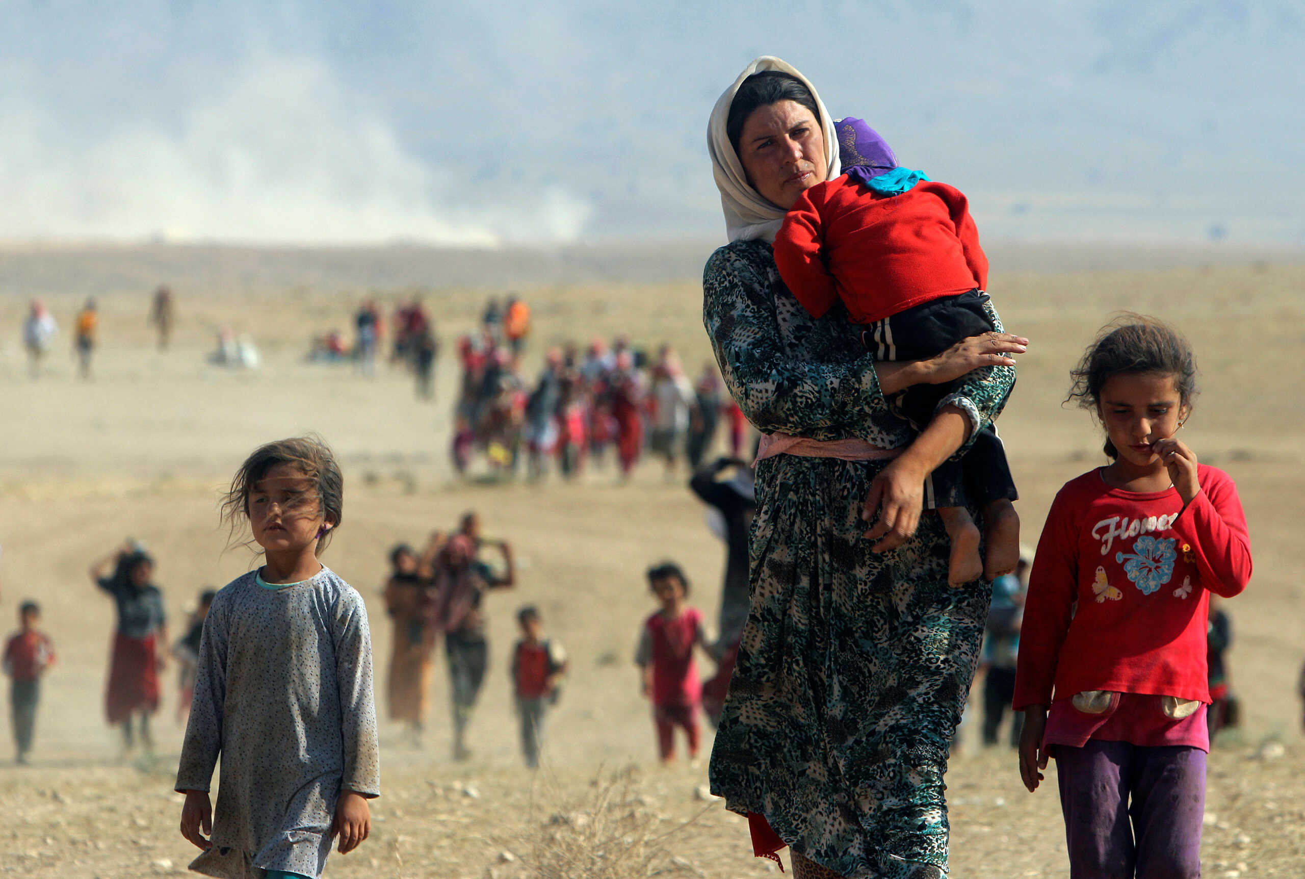 Displaced people from the minority Yazidi sect, fleeing violence from forces loyal to the Islamic State in Sinjar town, walk towards the Syrian border on the outskirts of Sinjar mountain near the Syrian border town of Elierbeh of Al-Hasakah Governorate in this August 11, 2014. REUTERS