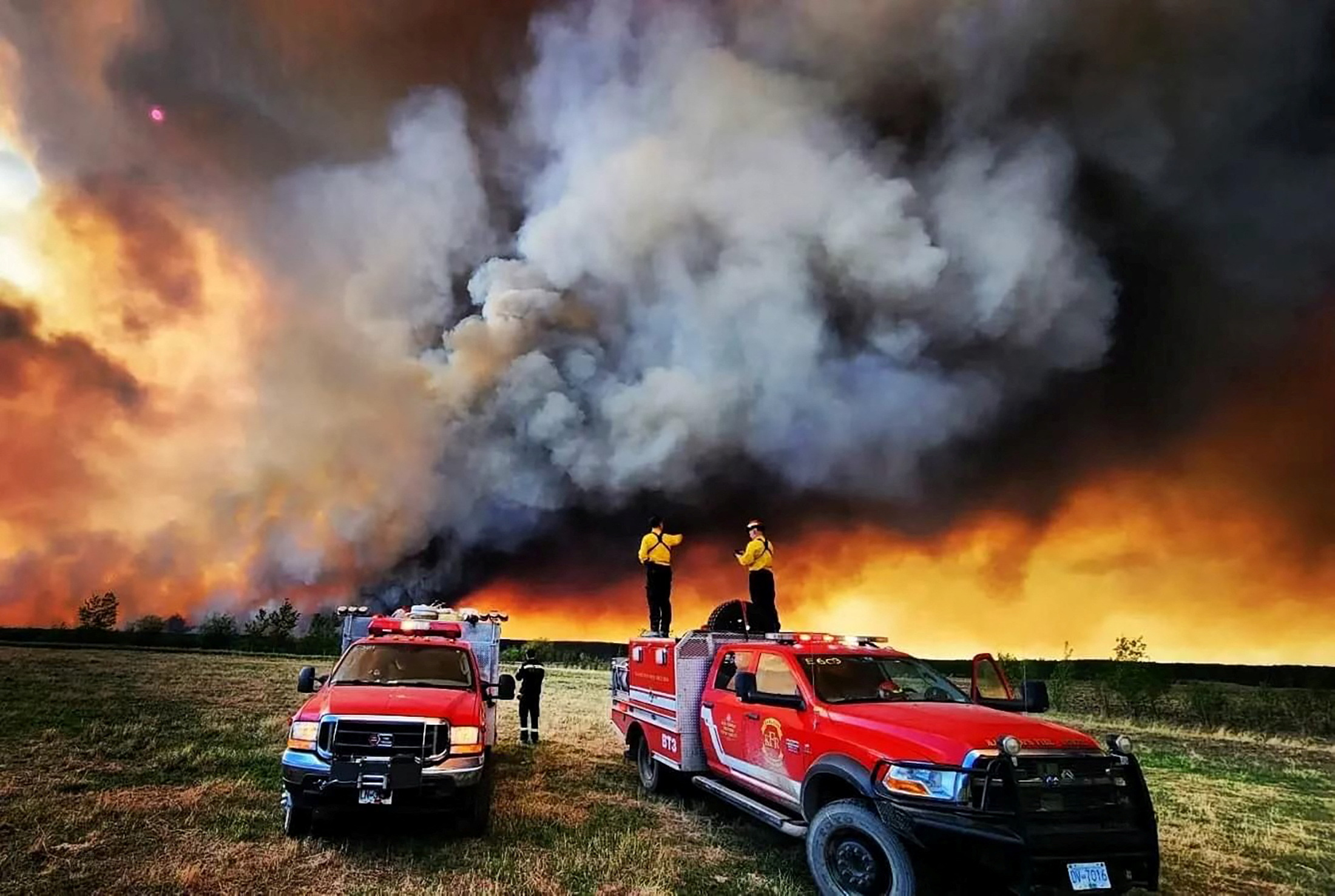 Firefighters stand on a Kamloops Fire Rescue truck at a wildfire near Fort St. John, British Columbia, Canada May 14, 2023. Kamloops Fire Rescue