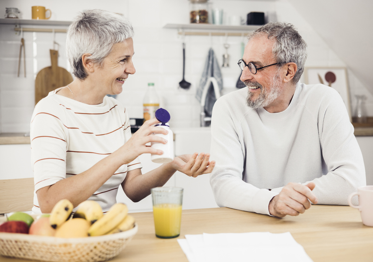 Portrait of a happy senior couple enjoying at home, drinking juice and using vitamins.