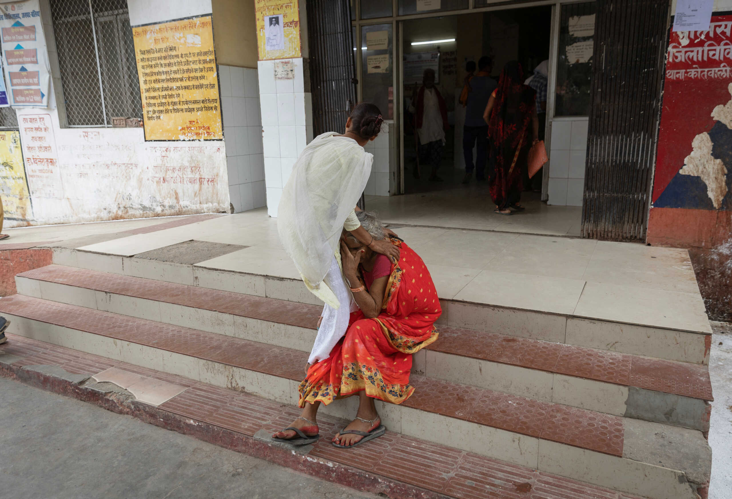 A girl holds her mother, who is suffering from breathing difficulties, as she sits at the entrance of an emergency ward after arriving at a hospital in district Ballia in the northern state of Uttar Pradesh, India, June 21, 2023. REUTERS