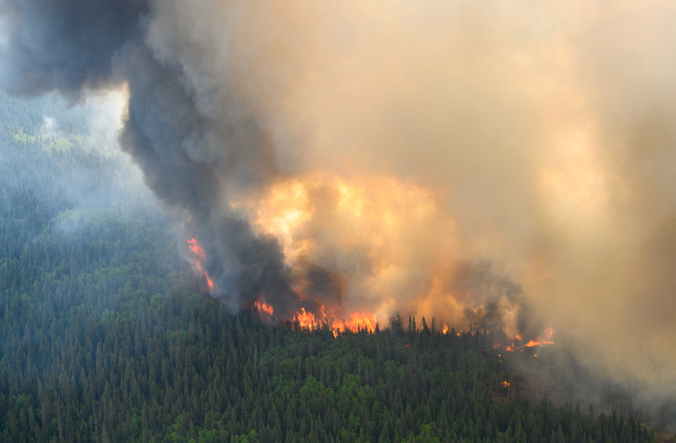 Flames reach upwards along the edge of a wildfire as seen from a Canadian Forces helicopter surveying the area near Mistissini, Quebec, Canada June 12, 2023.   Cpl Marc-Andre Leclerc