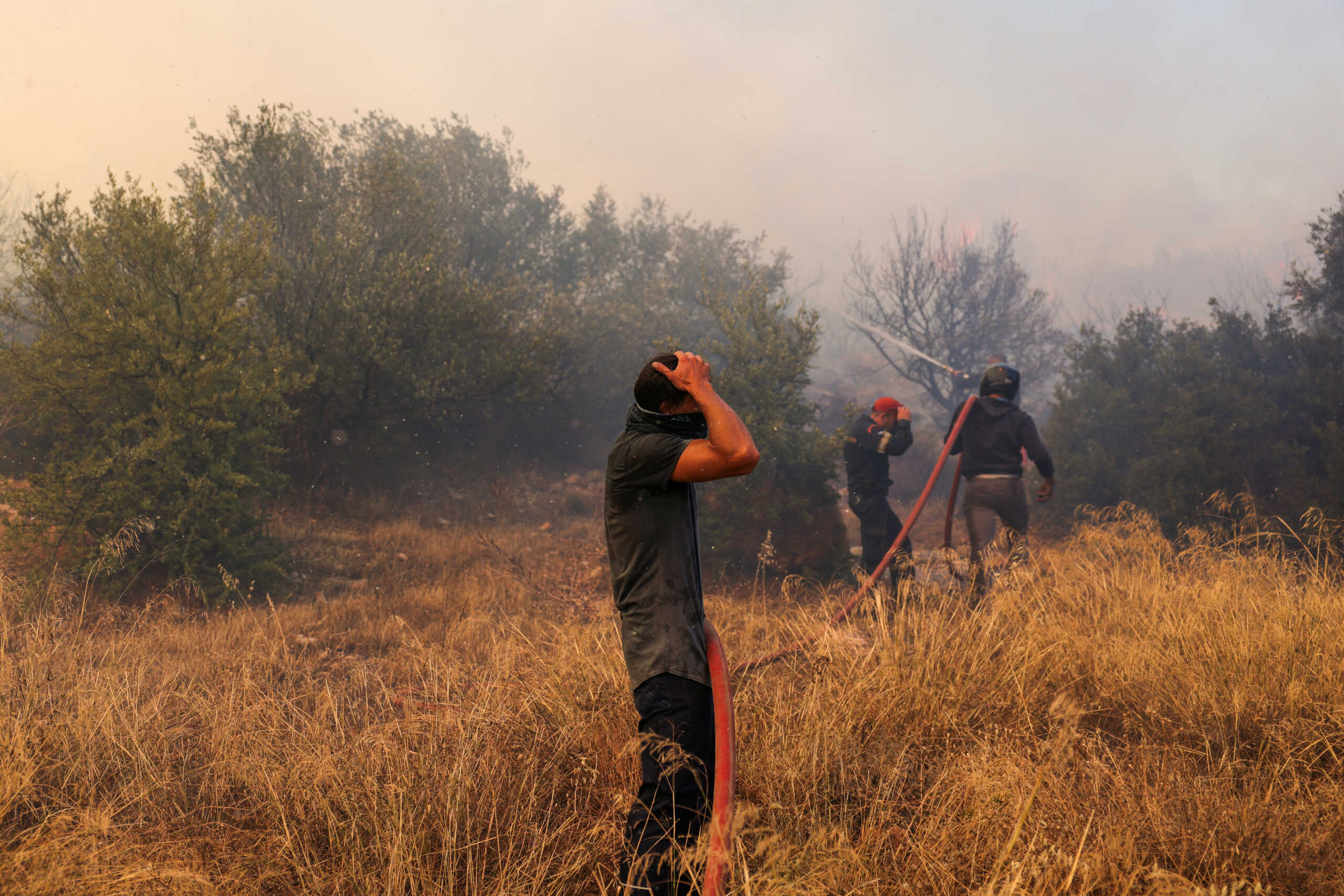 A volunteer reacts, as a wildfire burns in Kouvaras, near Athens, Greece, July 17, 2023. REUTERS