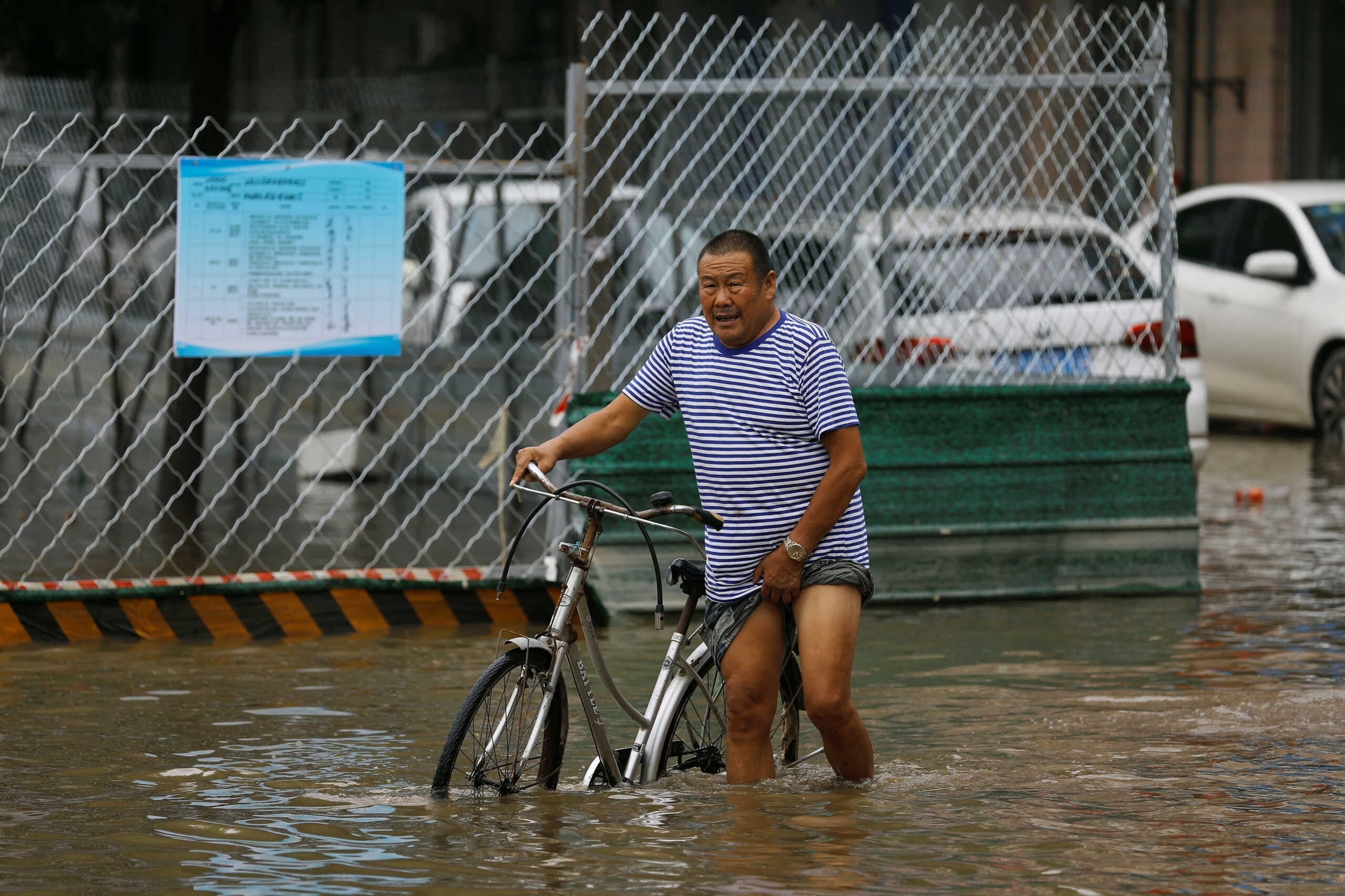 A man with a bicycle wades through floodwaters after remnants of Typhoon Doksuri brought rains and floods in Beijing, China August 2, 2023. REUTERS