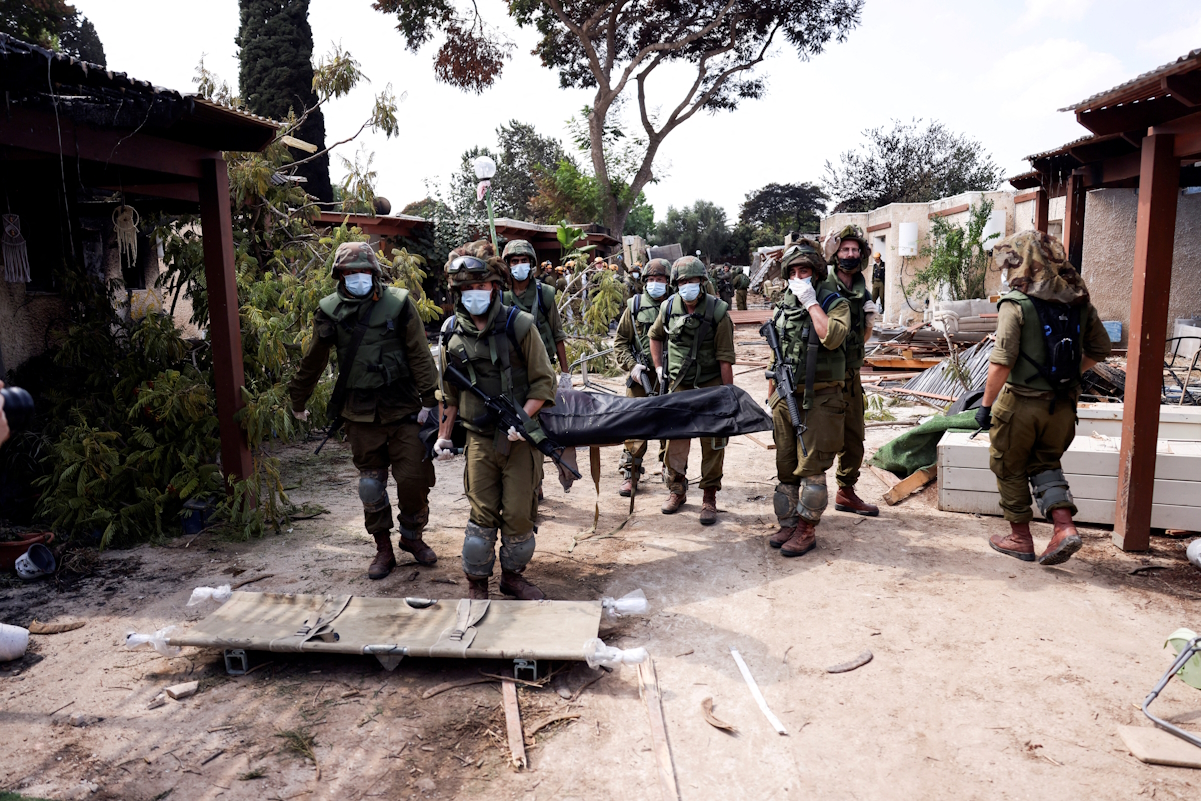 Israeli soldiers carry the body of a victim of an attack by militants from Gaza at Kibbutz Kfar Aza, in southern Israel, October 10, 2023. REUTERS