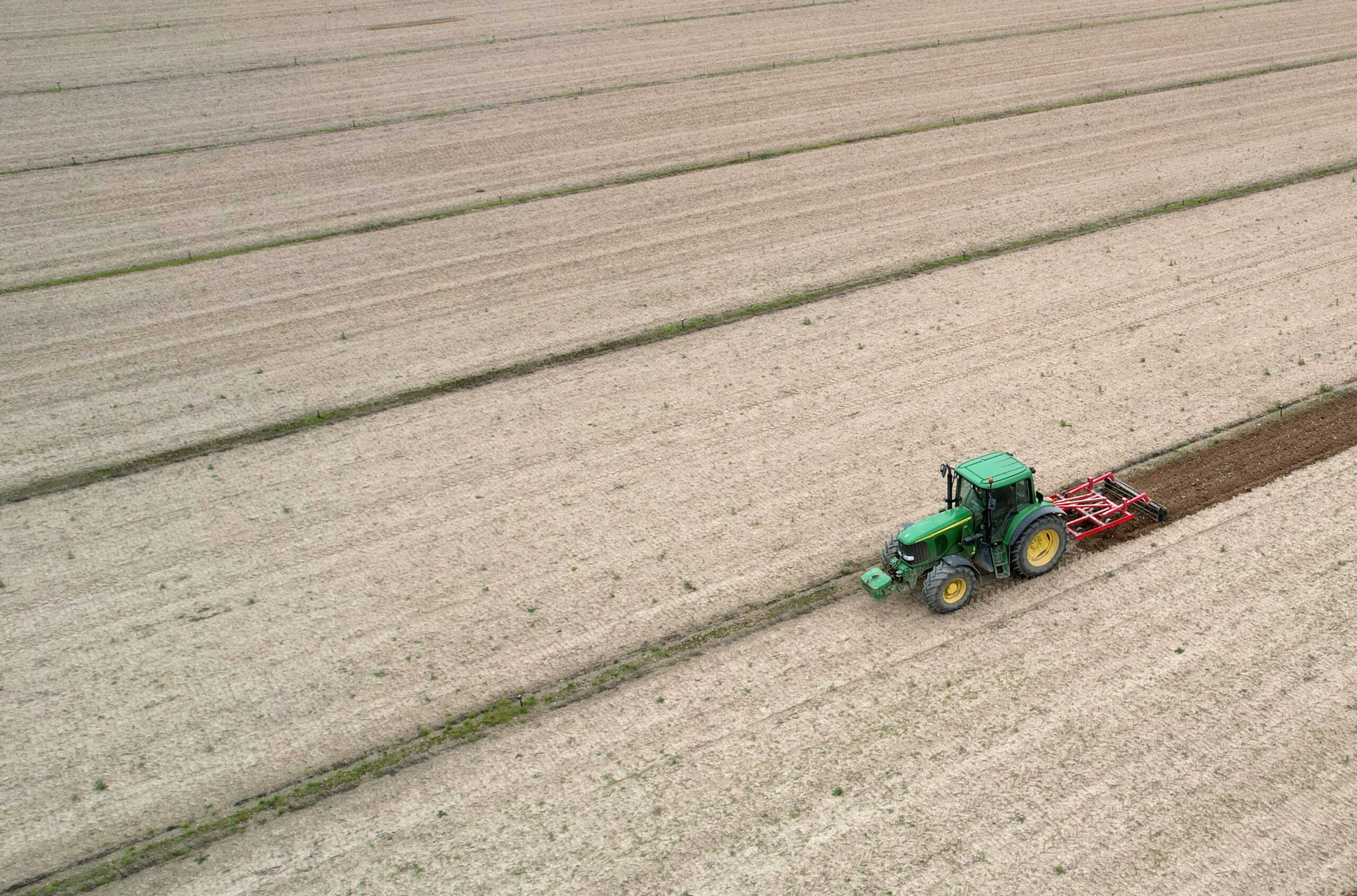 A drone view shows a farmer driving his tractor as he works in his field in Vieillevigne, France, April 16, 2024. REUTERS