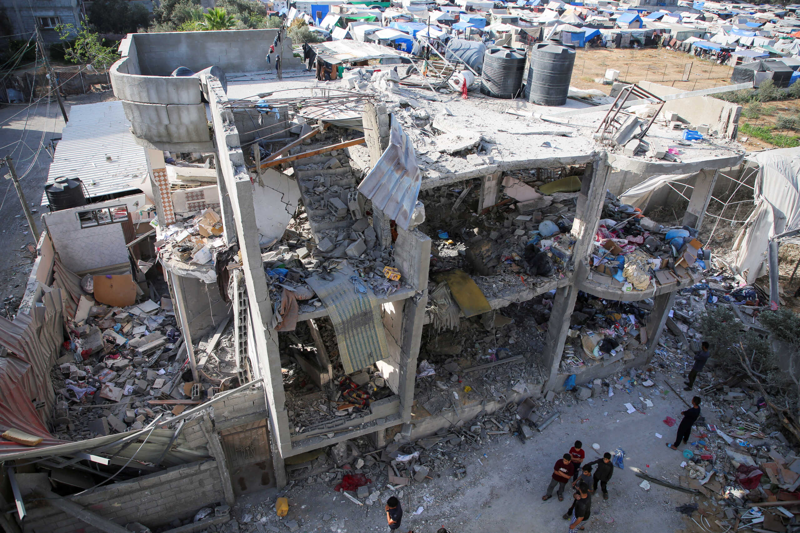 People stand next to a house damaged in an Israeli strike, amid the ongoing conflict between Israel and the Palestinian Islamist group Hamas, in Rafah, in the southern Gaza Strip, May 3, 2024. REUTERS