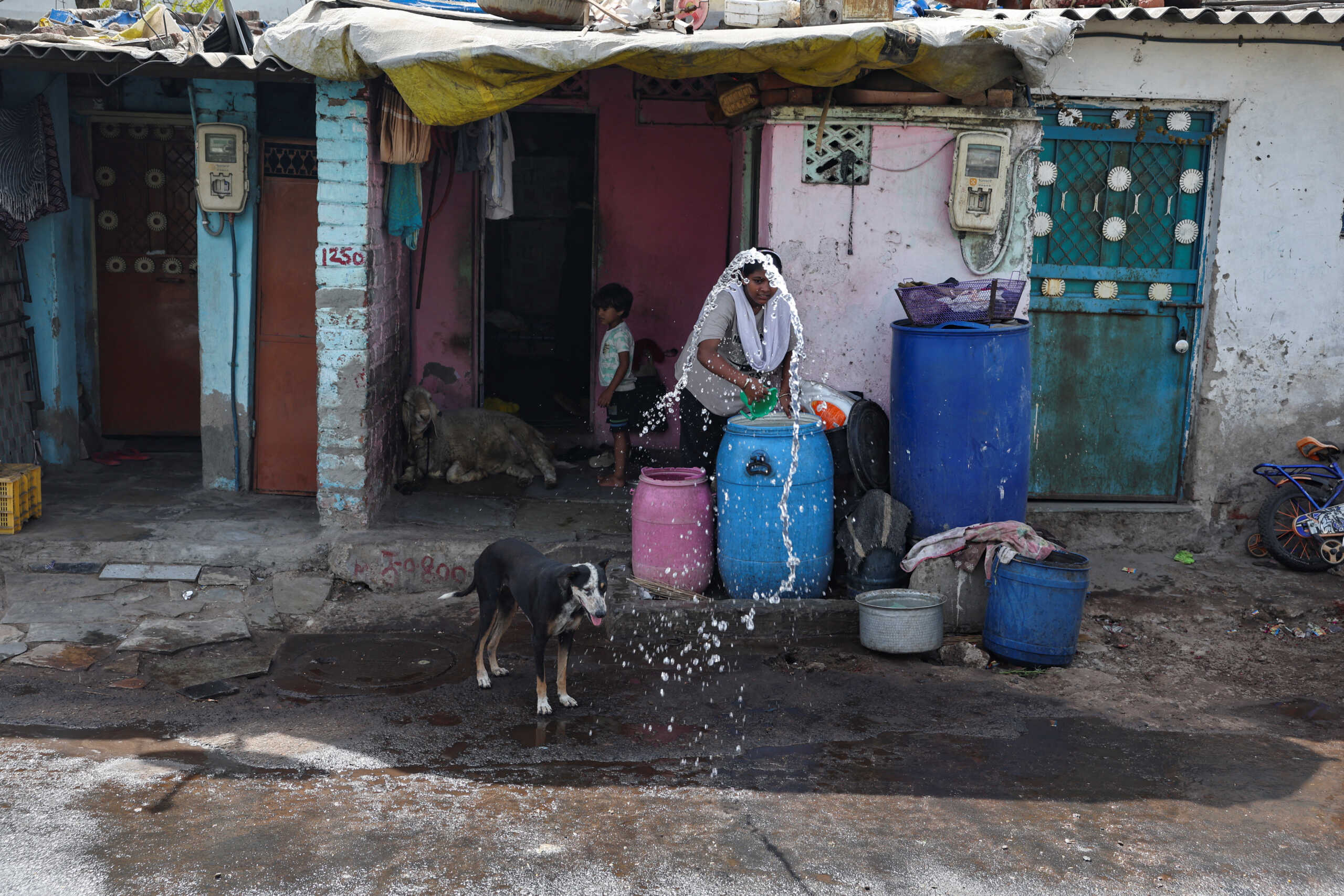 A woman sprays water in front of her roadside home during the heat wave in Ahmedabad, India, May 30, 2024. REUTERS