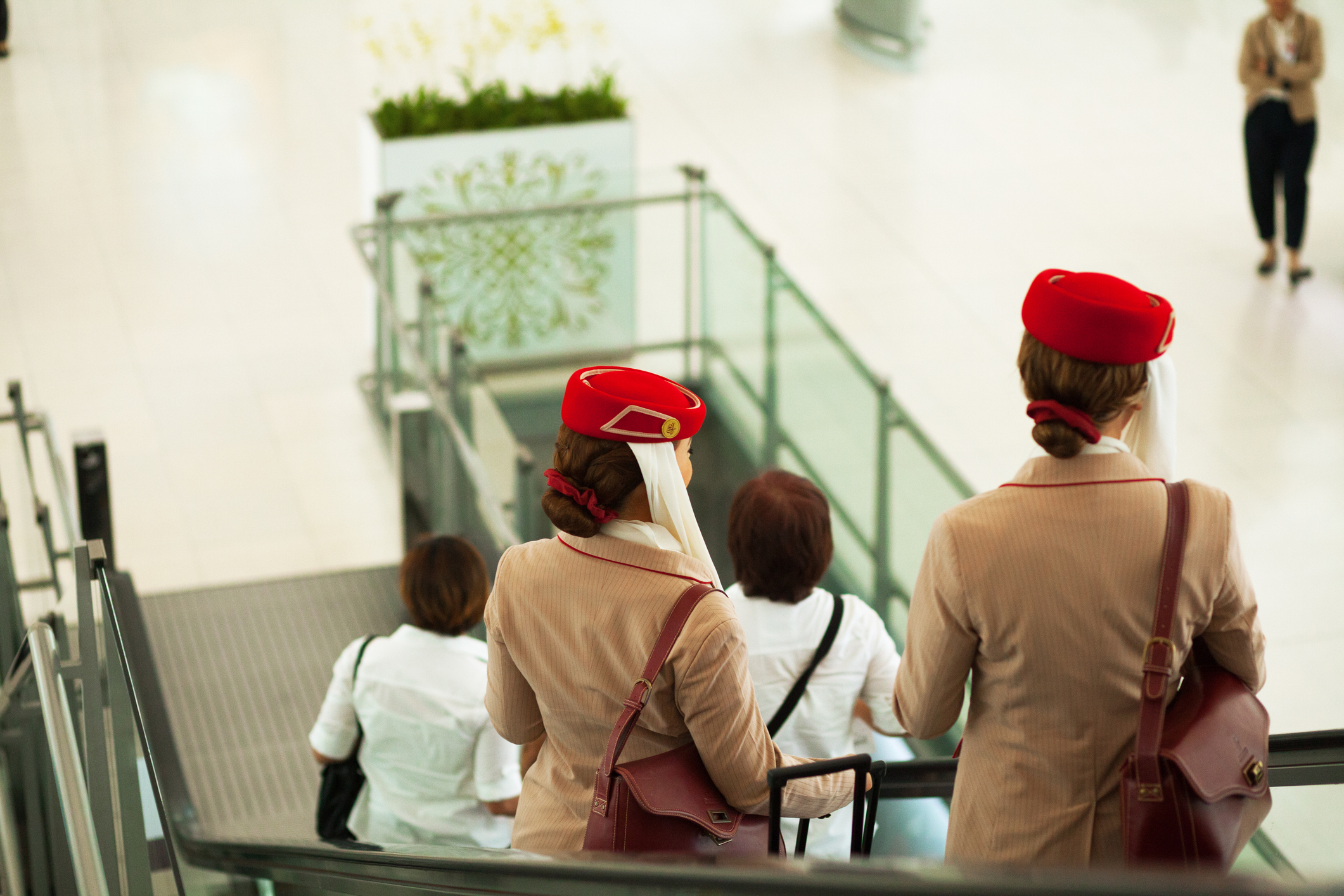 Bangkok, Thailand - July 1, 2016: Capture of two stewardesses of Emirates airlines on escalator in departure hall of airport Bangkok Survanabhumi. Below are passengers.