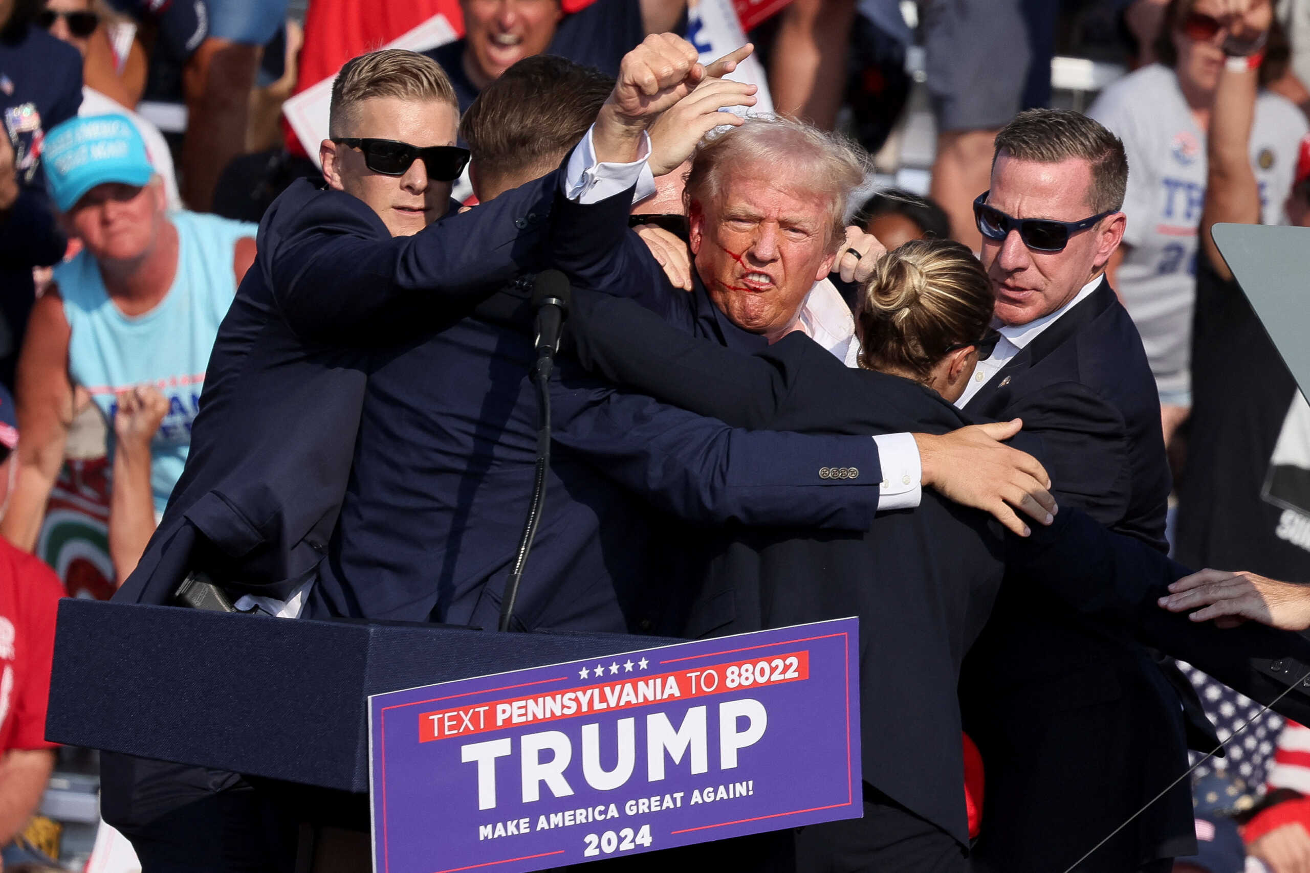 Republican presidential candidate and former U.S. President Donald Trump gestures with a bloodied face while he is assisted by U.S. Secret Service personnel after he was shot in the right ear during a campaign rally at the Butler Farm Show in Butler, Pennsylvania, U.S., July 13, 2024. REUTERS