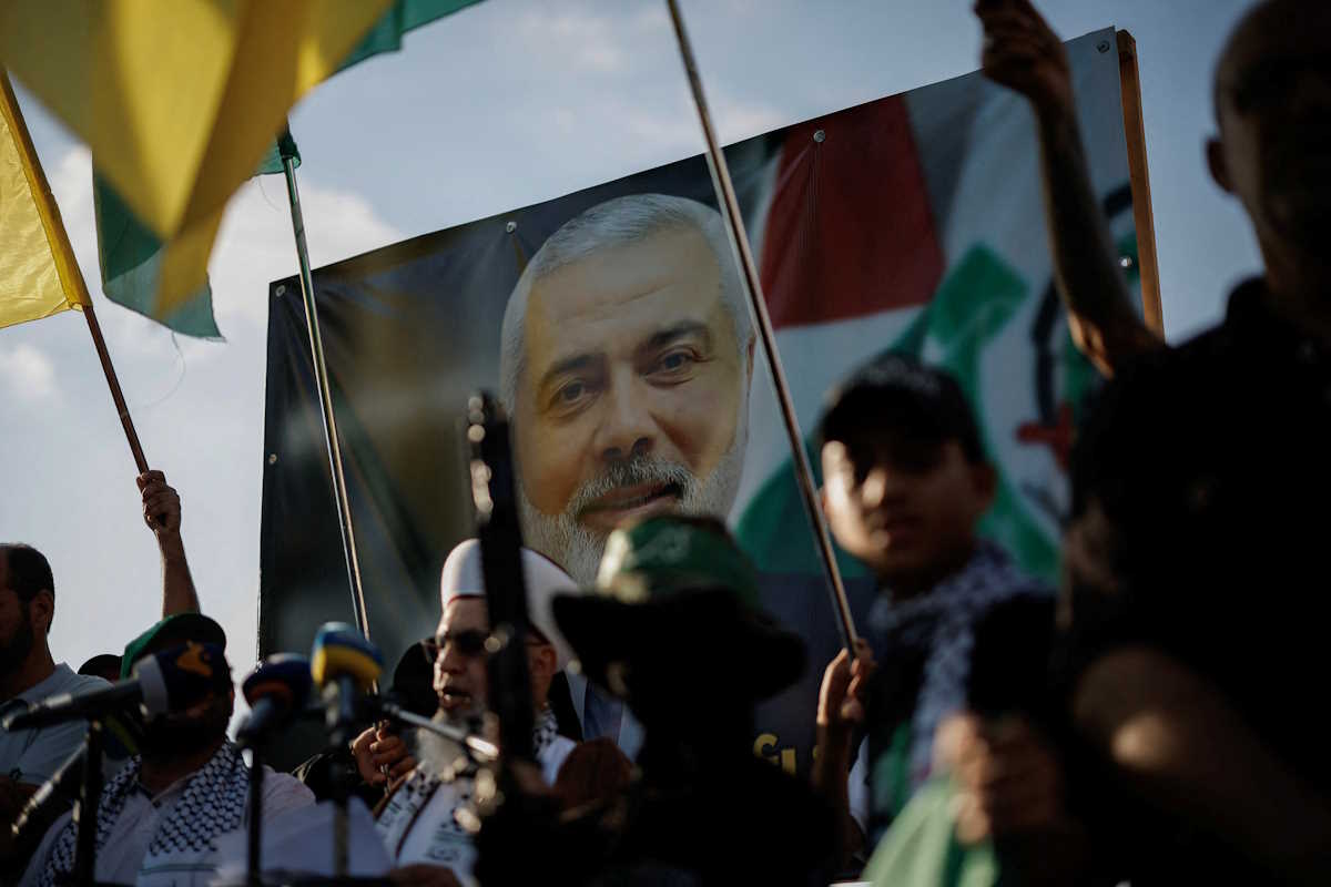 Demonstrators hold flags and weapons next to an image of late Hamas leader Ismail Haniyeh, during a protest to condemn his assassination in Iran, in Sidon, Lebanon, July 31, 2024. REUTERS