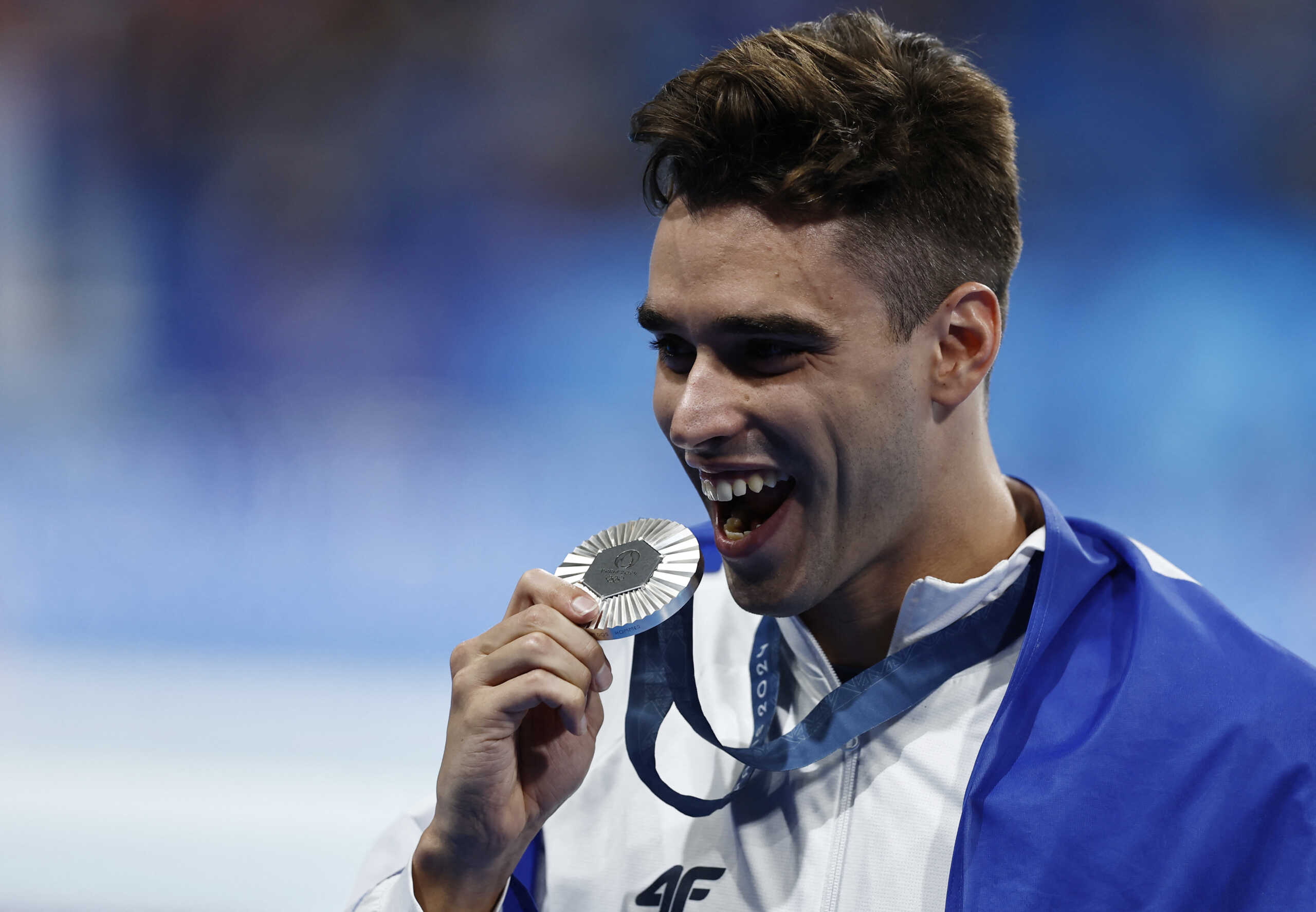 Paris 2024 Olympics - Swimming - Men's 200m Backstroke Victory Ceremony - Paris La Defense Arena, Nanterre, France - August 01, 2024. Silver medallist Apostolos Christou of Greece celebrates with his silver medal and the flag of Greece. REUTERS