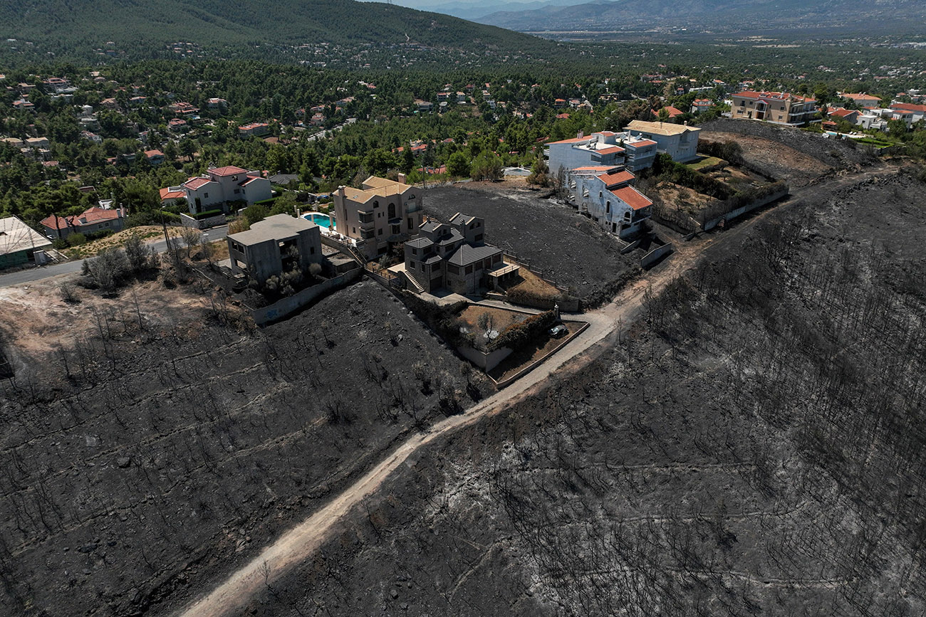 FILE PHOTO: A drone view shows a charred forest area on a hillside next to houses, following a wildfire, in Dionysos, near Athens, Greece, August 14, 2024. REUTERS