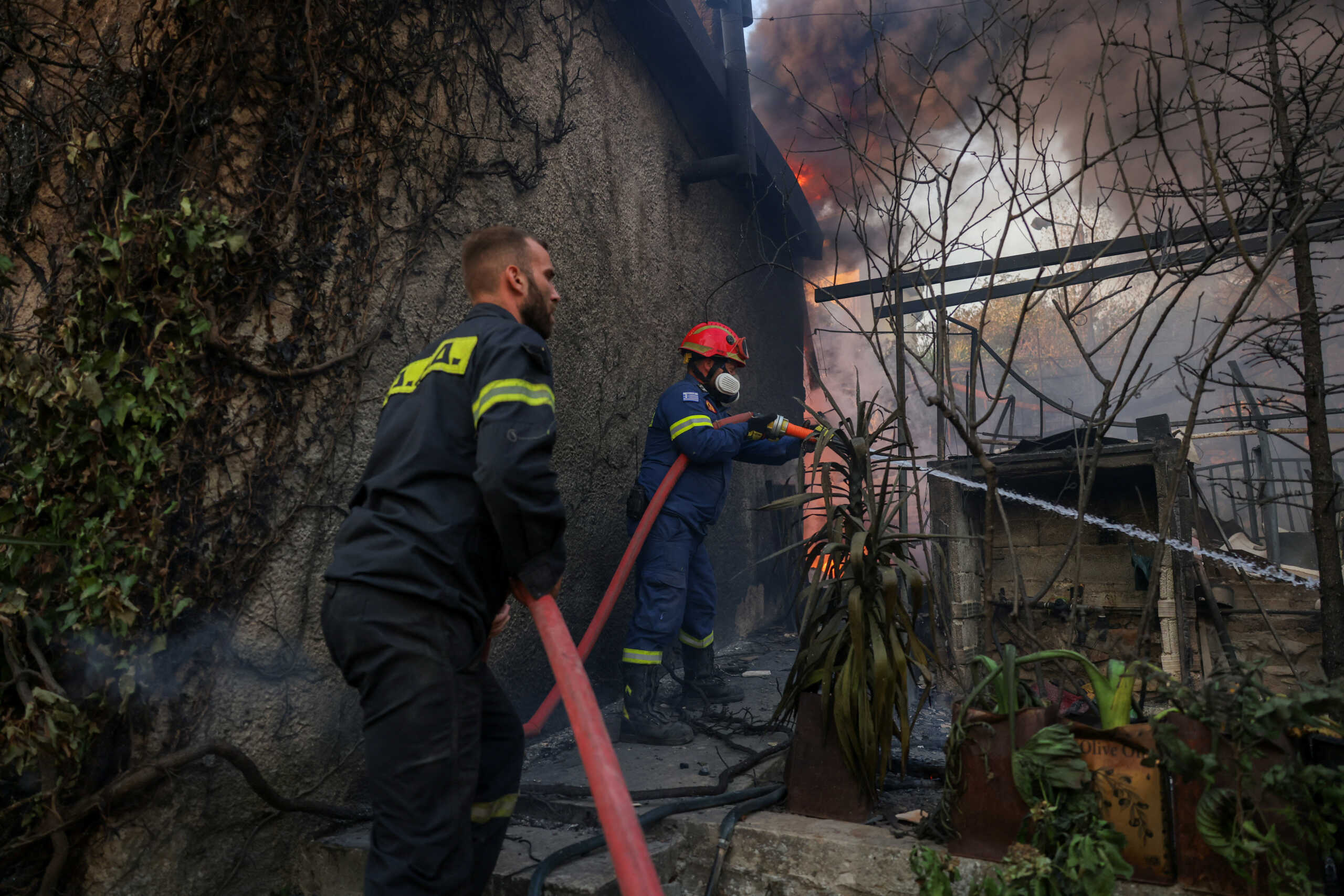 Firefighters try to extinguish a wildfire burning a house in Dionysos, Greece, August 12, 2024. REUTERS