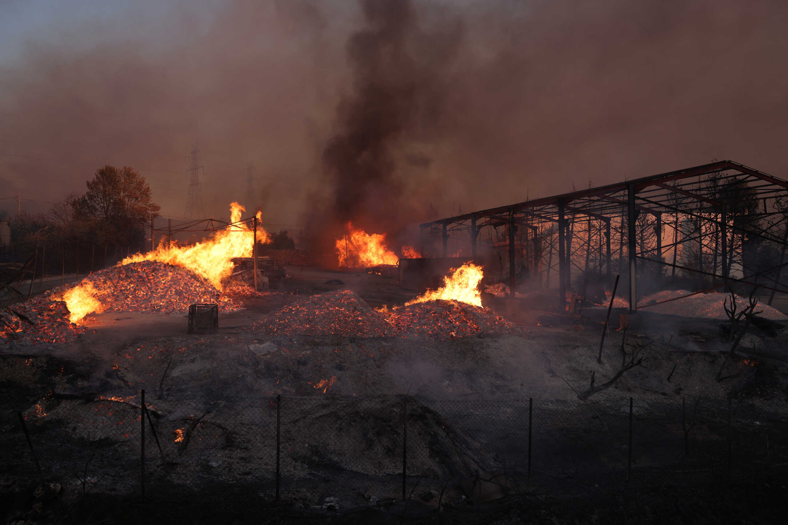 A factory yard is seen in flames as a wildfire burns in Vrilissia near Athens, Greece, August 12, 2024. REUTERS