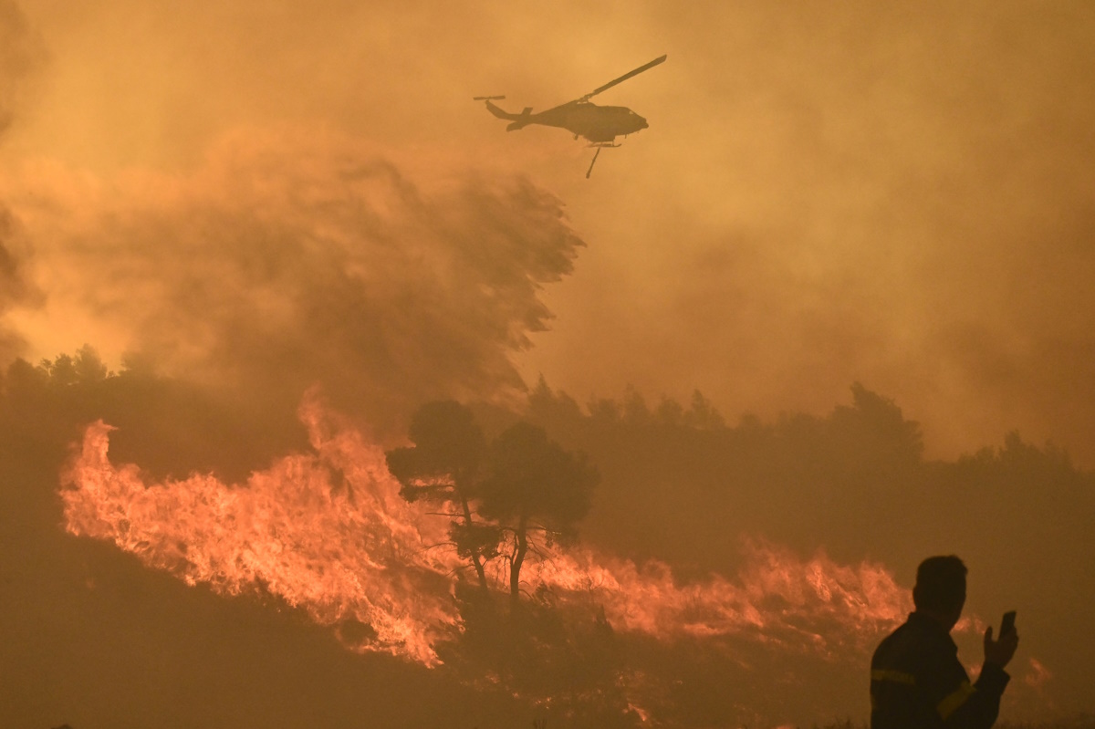 A firefighting helicopter makes a water drop as a wildfire burns in the village of Varnava, near Athens, Greece, August 11, 2024. Kostas Tzoumas