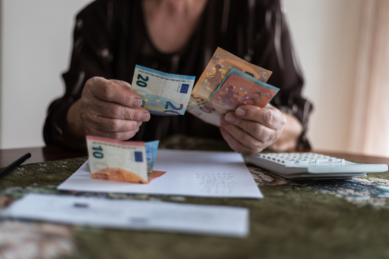 Finances, savings, annuity insurance and people concept - senior woman with calculator and bills is counting money at home. Senior woman is calculating taxes at home.Counts the pension.