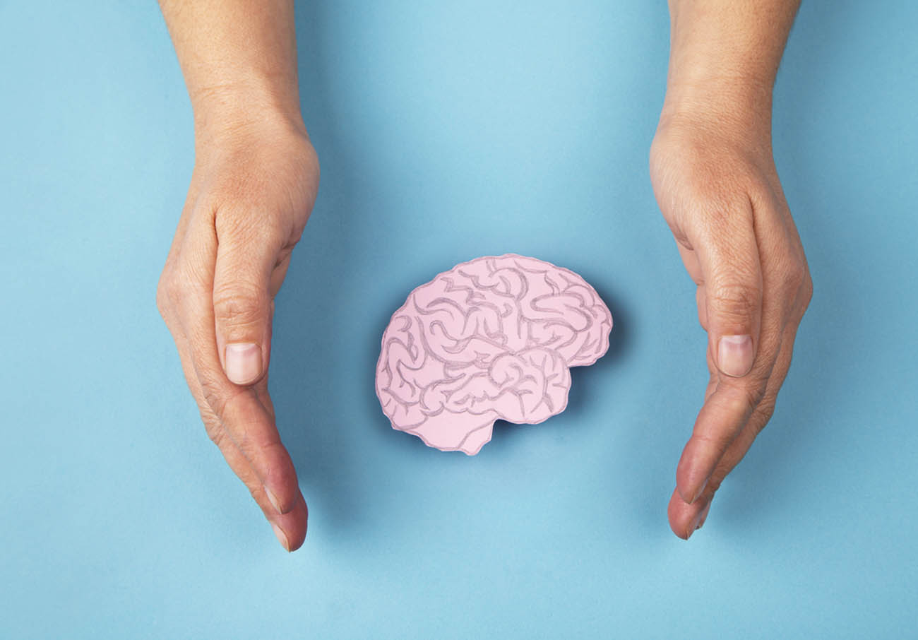 Human brain made of paper and hands isolated on blue background