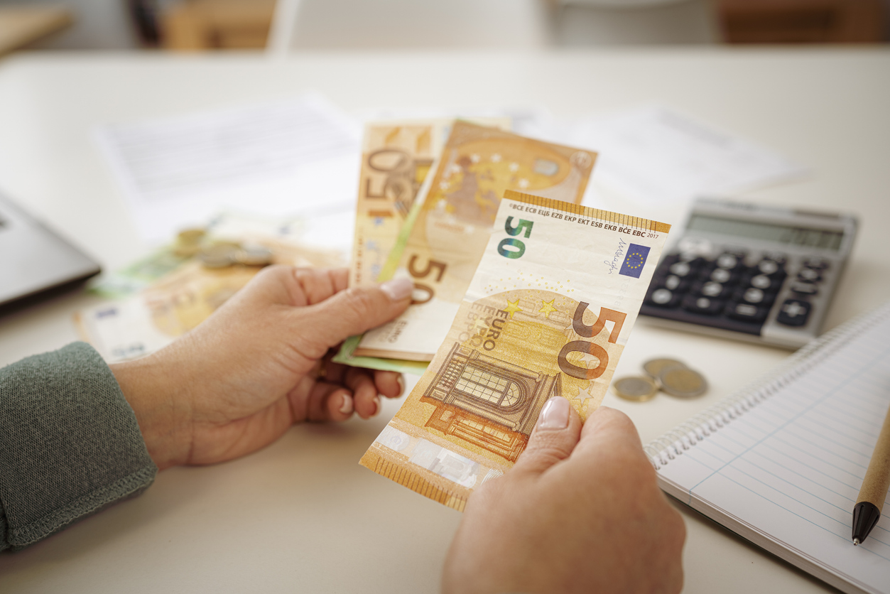 Close-up of woman's hands counting Euro banknotes planning home finances.