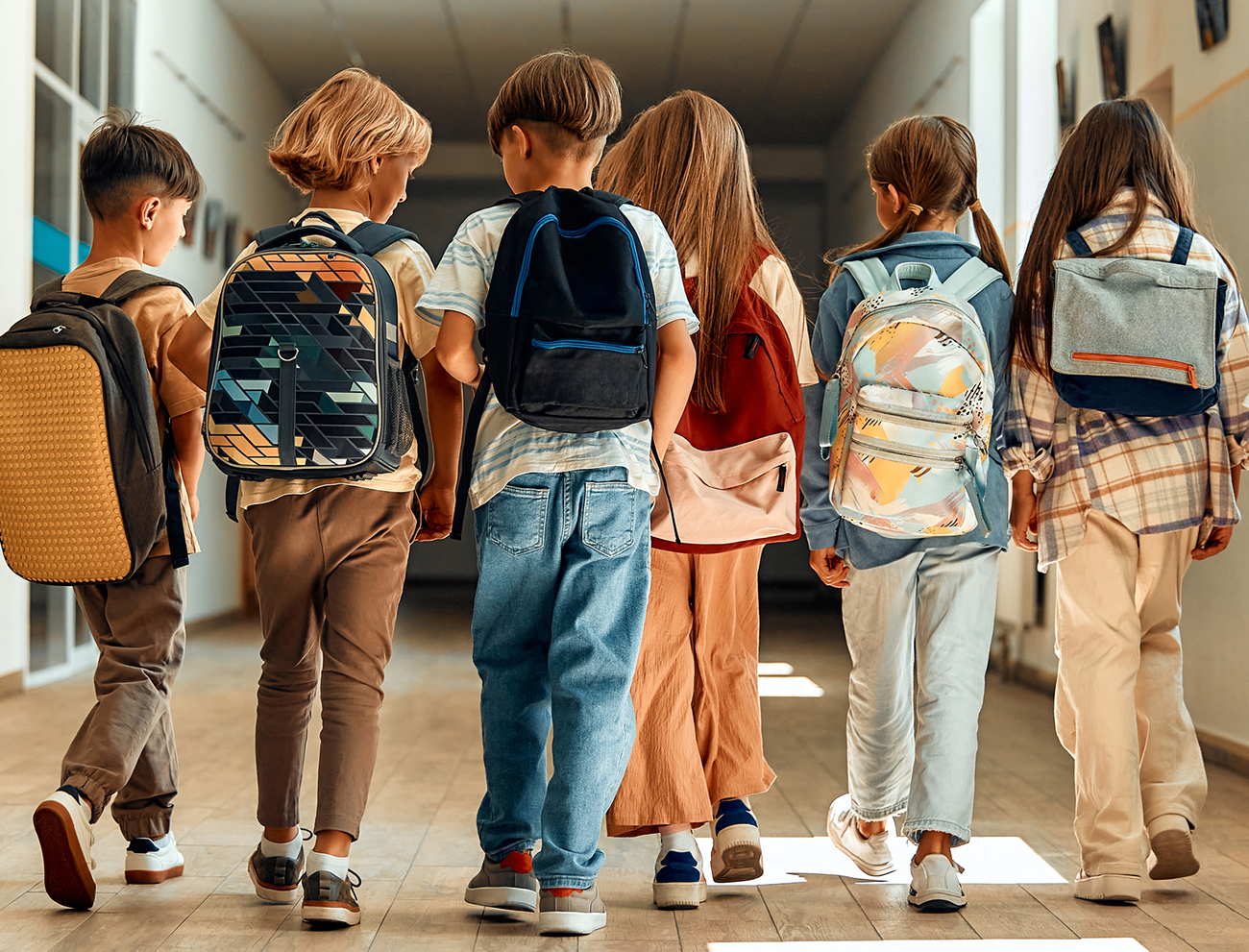 Back to school. A group of schoolchildren with backpacks walk along the school corridor during recess. Education and science concept.