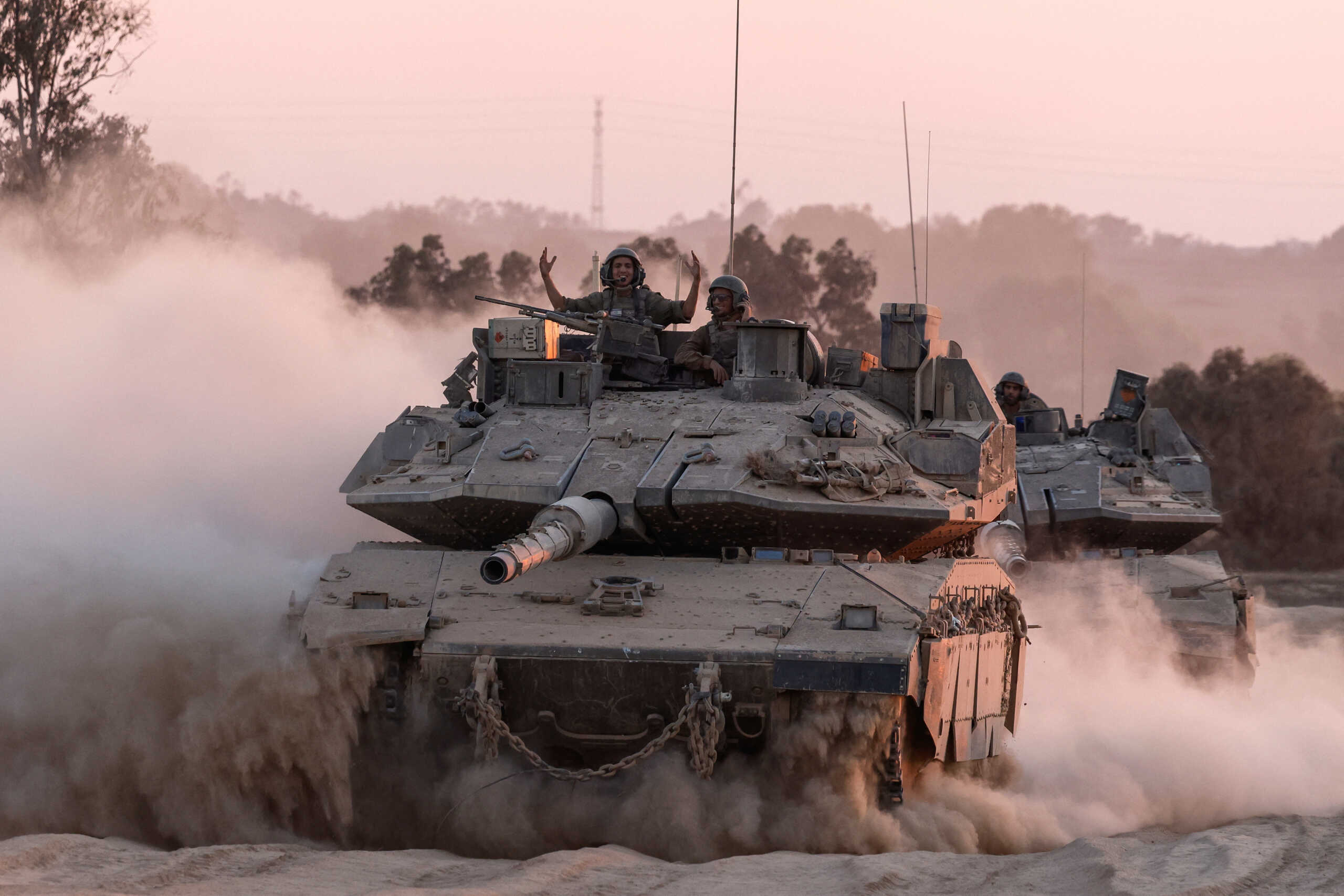 An Israeli soldier gestures on a top of a tank as Israeli military vehicles manoeuvre, near the Israel-Gaza border, amid the Israel-Hamas conflict, August 21, 2024. REUTERS