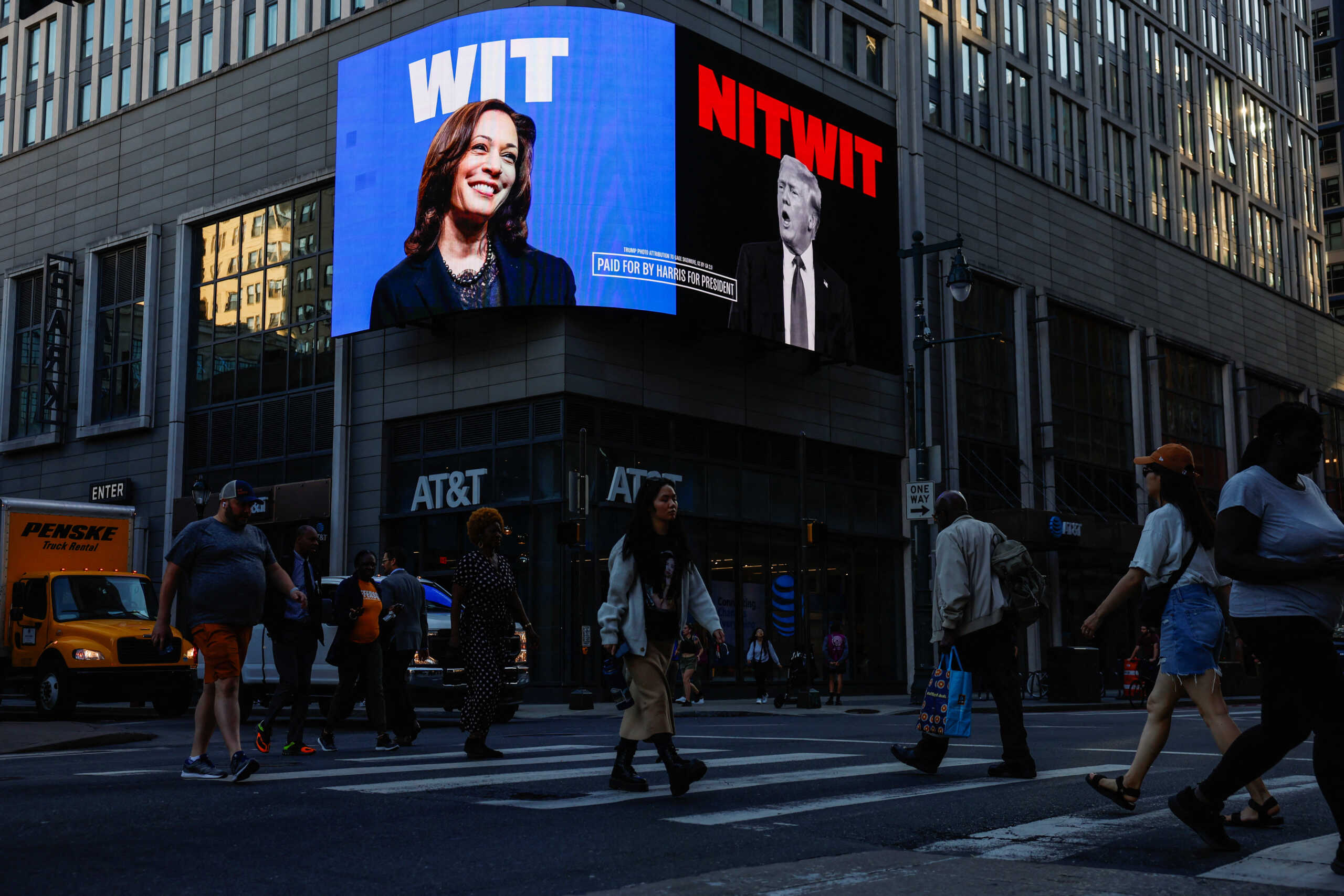 People walk as a digital billboard shows pictures of Republican presidential nominee and former U.S. President Donald Trump and Democratic presidential nominee and U.S. Vice President Kamala Harris, ahead of the debate between Donald Trump and Kamala Harris, in Philadelphia, Pennsylvania, U.S., September 10, 2024. REUTERS