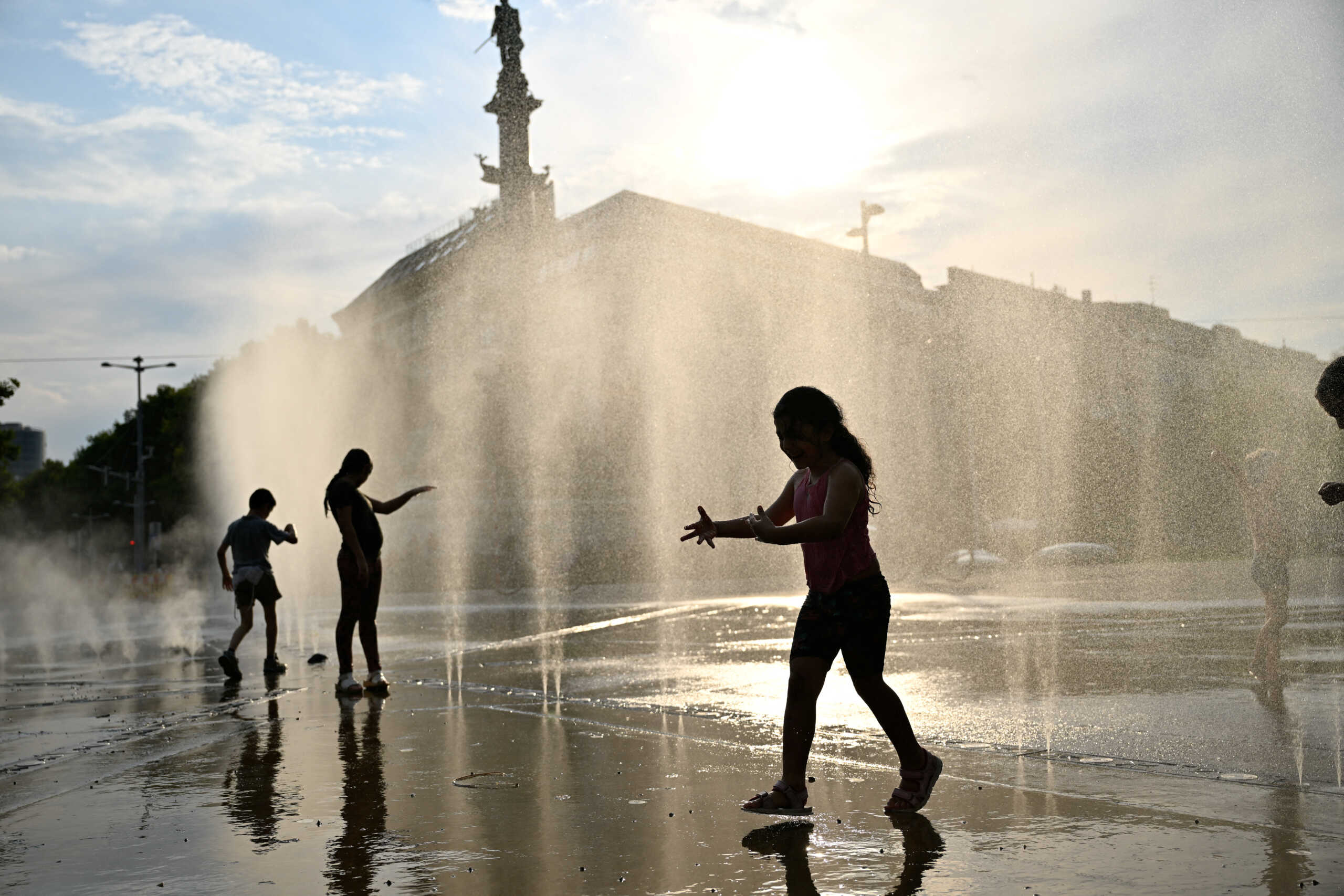 Children play under a water sprinkler during a heat wave in Vienna, Austria, August 14, 2024. REUTERS