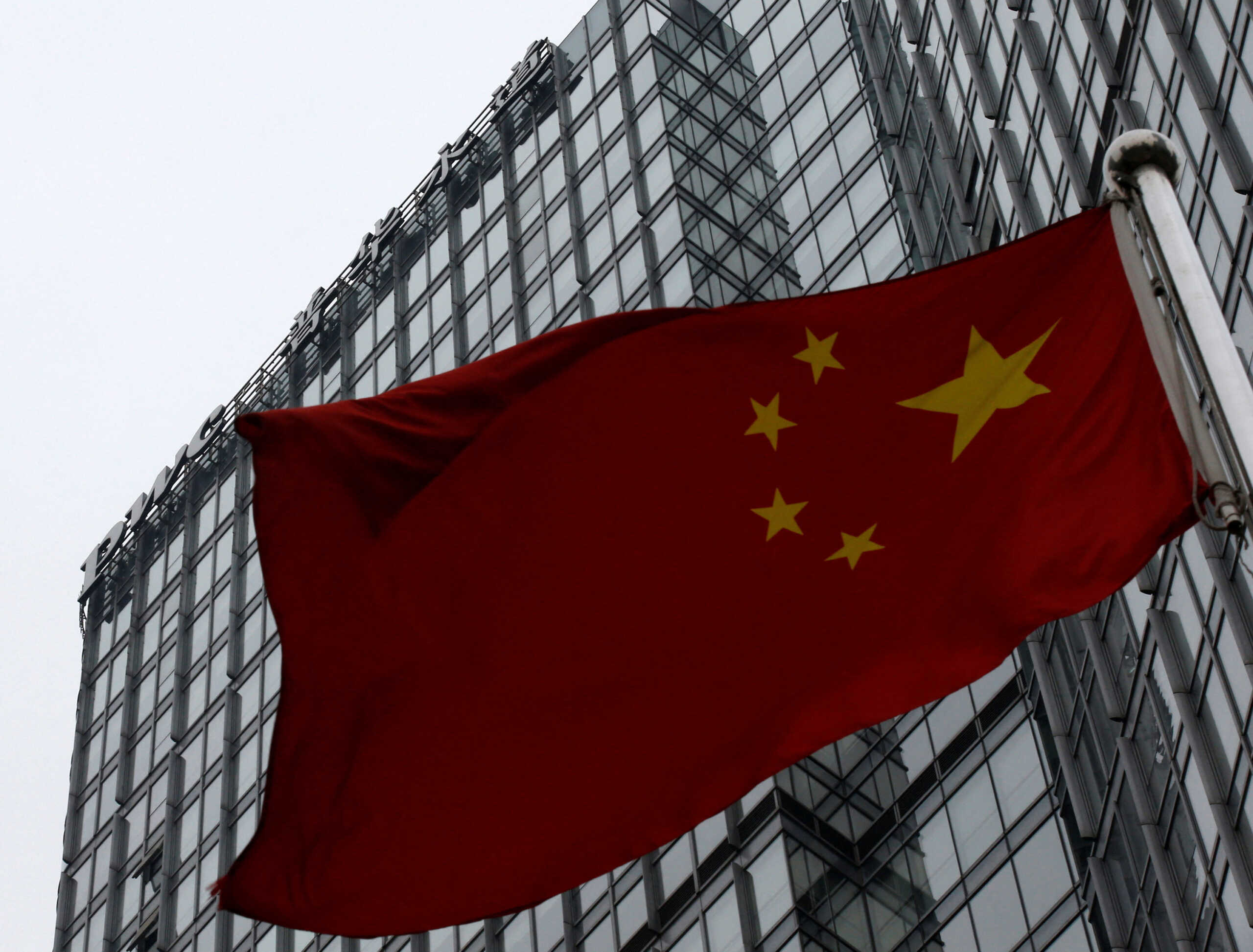 FILE PHOTO: A building housing the PricewaterhouseCoopers (PWC) branch office stands behind a Chinese national flag in Beijing January 24, 2014.  REUTERS