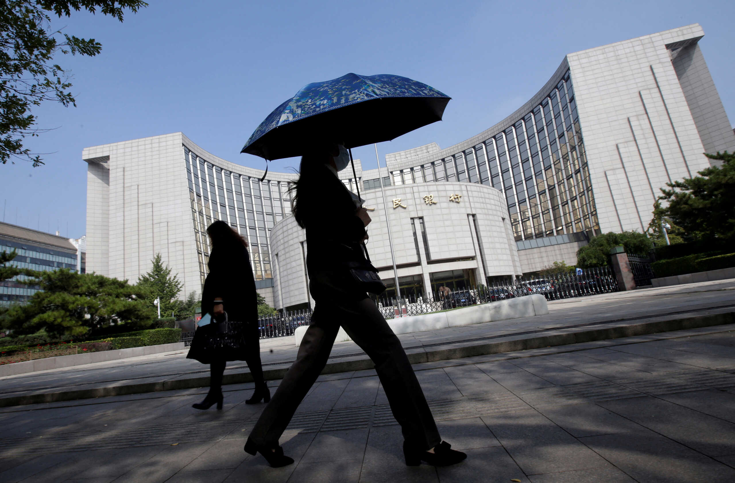 FILE PHOTO: People walk past the headquarters of the People's Bank of China (PBOC), the central bank, in Beijing, China September 28, 2018. REUTERS