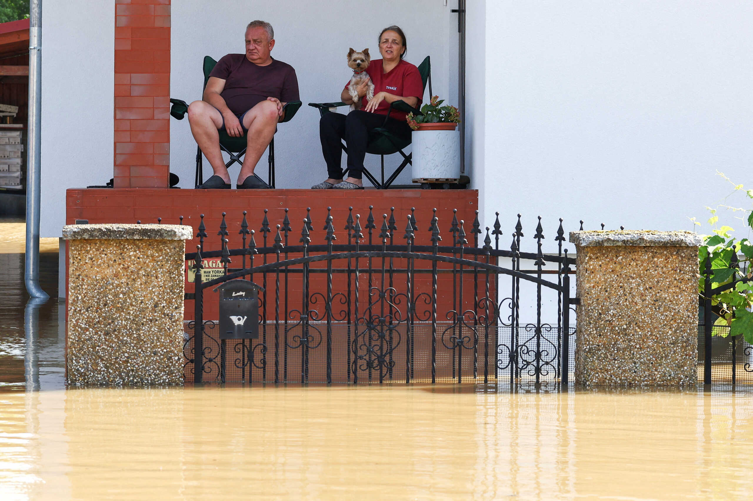 Flood affected residents sit by their front door, in an area flooded by the Nysa Klodzka river, following heavy rainfalls, in Lewin Brzeski, Poland, September 17, 2024. REUTERS