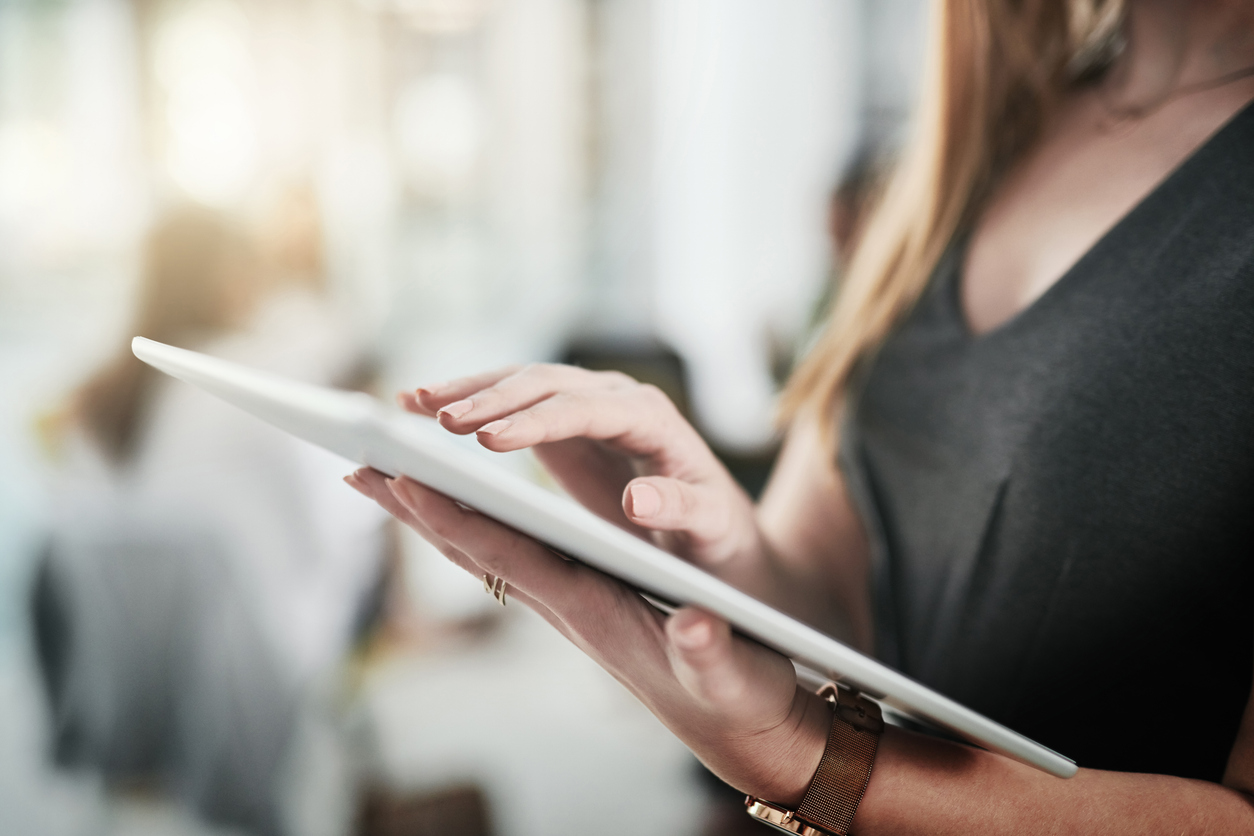 Cropped shot of an unrecognizable businesswoman standing alone and using a tablet in the office