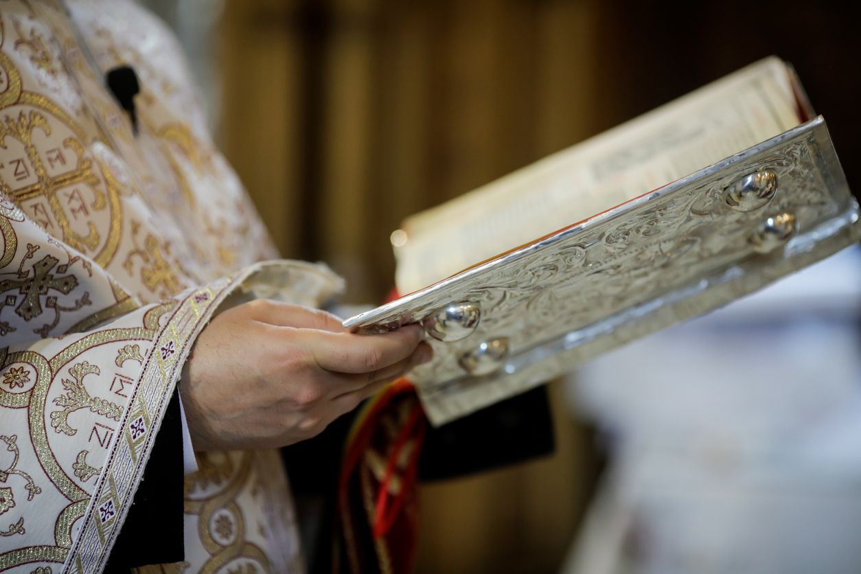 Bucharest, Romania - May 24, 2020: Details of an Orthodox priest reading from the Holy Bible during an Orthodox Baptism.