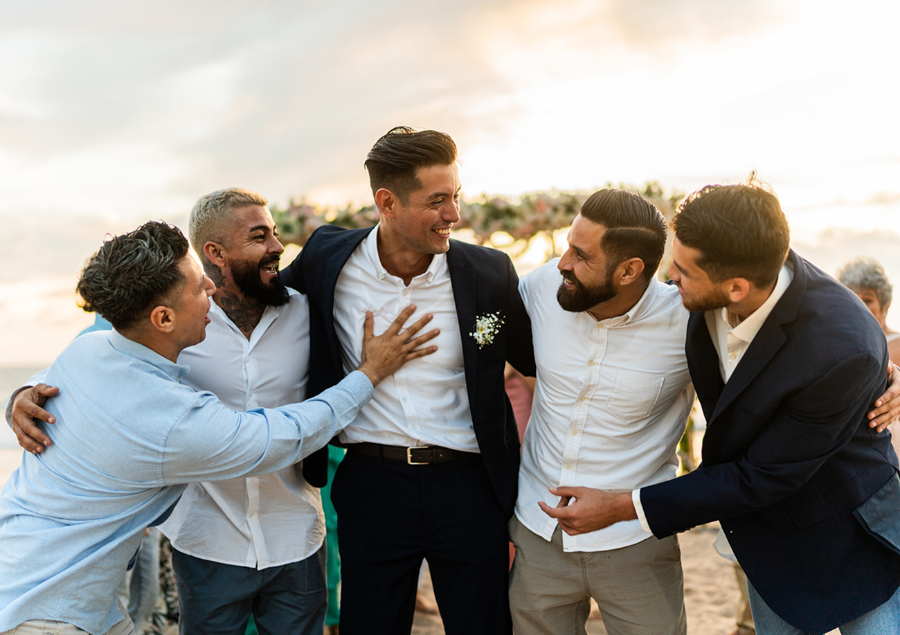 Groom talking with his friends in the wedding party on the beach