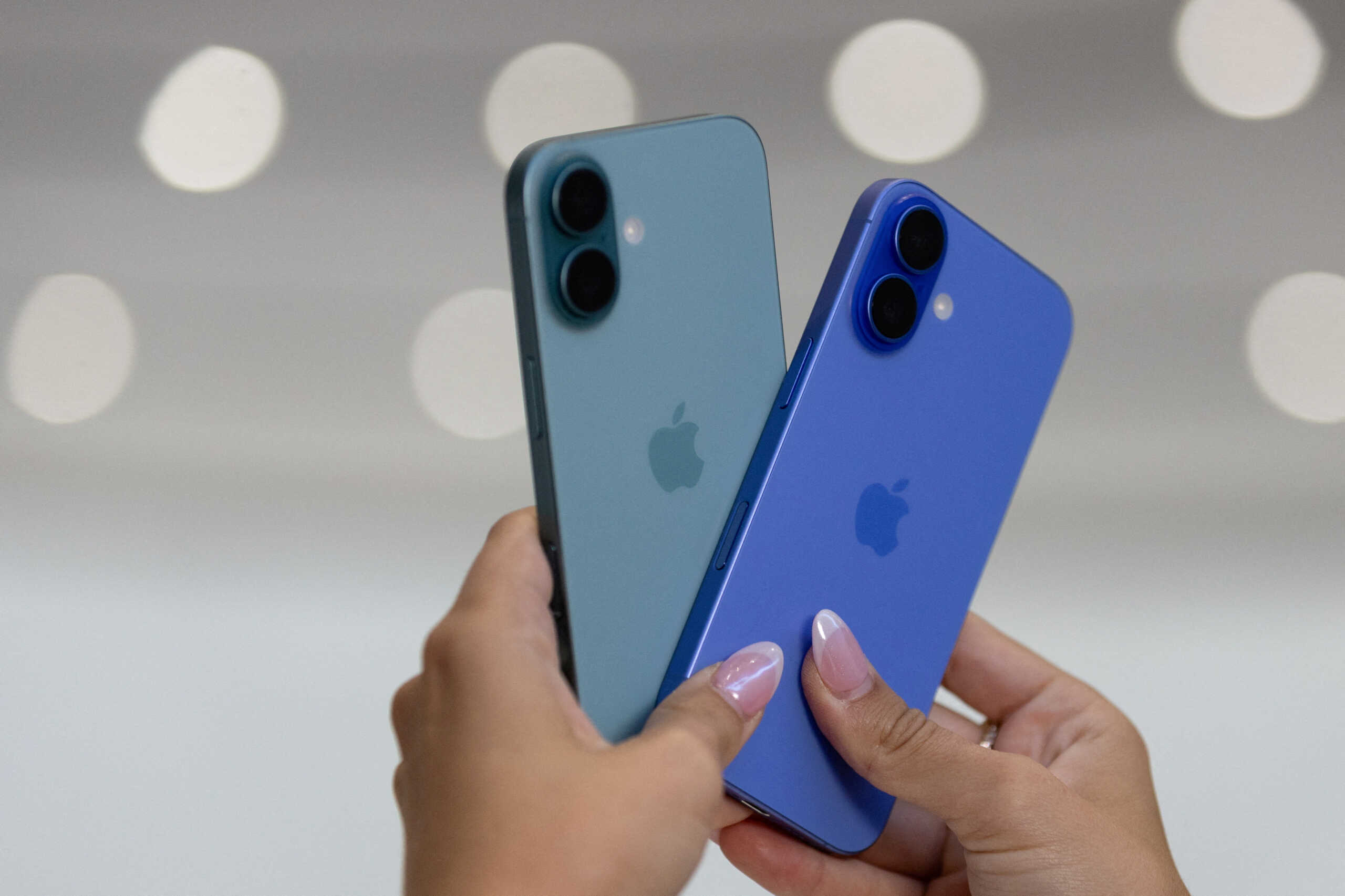 FILE PHOTO: An attendee holds two iPhones 16 as Apple holds an event at the Steve Jobs Theater on its campus in Cupertino, California, U.S. September 9, 2024. REUTERS